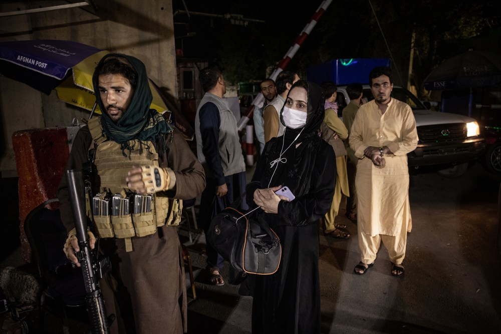 Zahra Nabi, a female journalist working for Bano TV, near Taliban fighters at a checkpoint after the first Taliban news conference following their takeover in Kabul on Aug. 17, 2021.