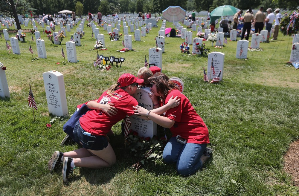 Leanne McCain, right, and her children embrace over her slain husband's grave at Arlington National Cemetery on May 28, 2012. Her husband, father-of-four Army SFC Johnathan McCain, was killed by a roadside bomb in Afghanistan in November 2011.