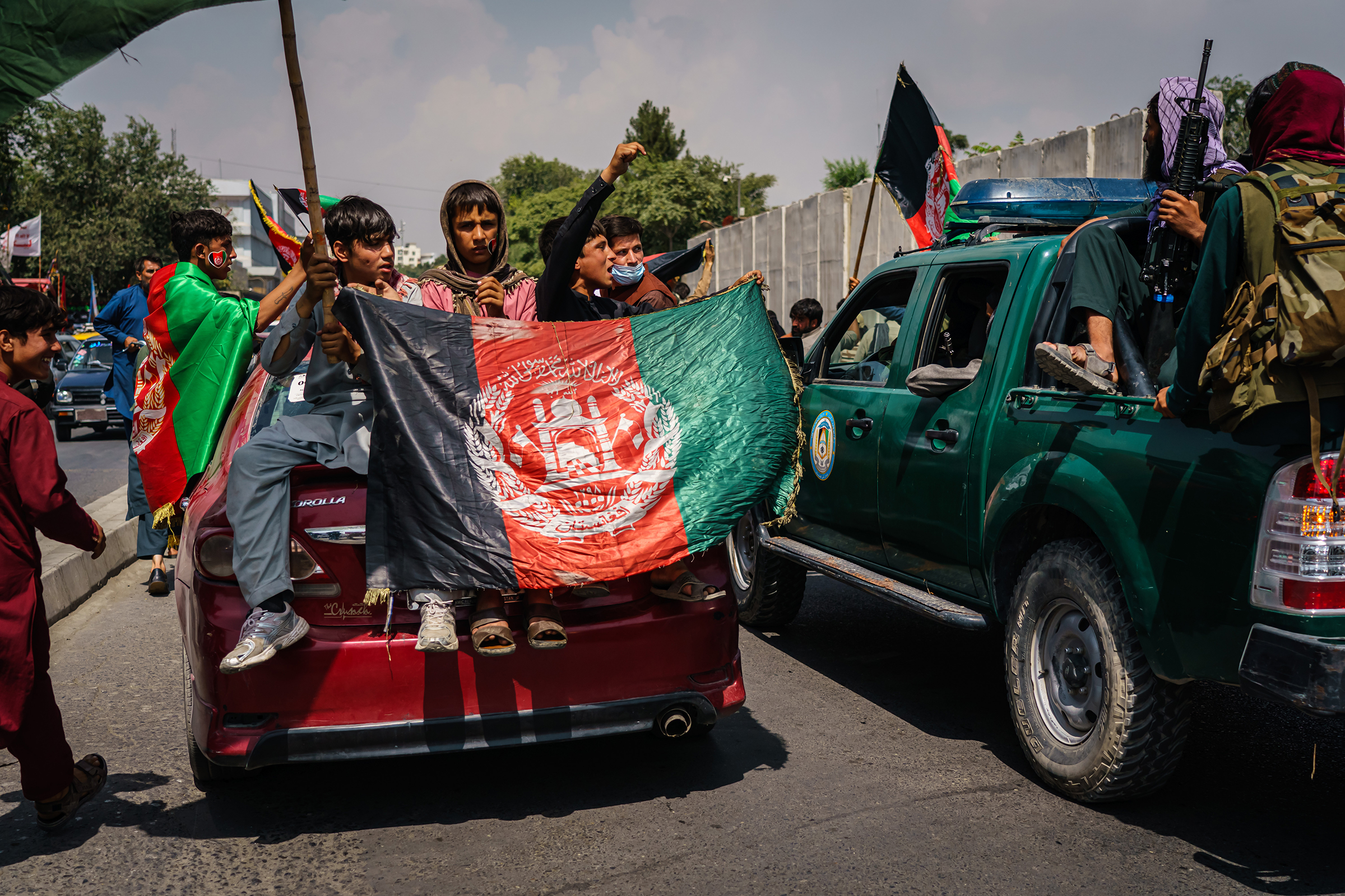 Afghans march while carrying banners and the flag of the Islamic Republic of Afghanistan, despite the presence of Taliban fighters, in Kabul on Aug. 19, 2021.