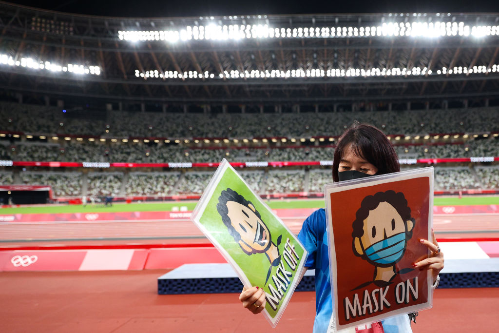 Photo team member Tomoko Mizushima holds Mask Off and Mask On signage on day fourteen of the Tokyo 2020 Olympic Games at Olympic Stadium on August 06, 2021 in Tokyo, Japan. (Patrick Smith&mdash;Getty Images)