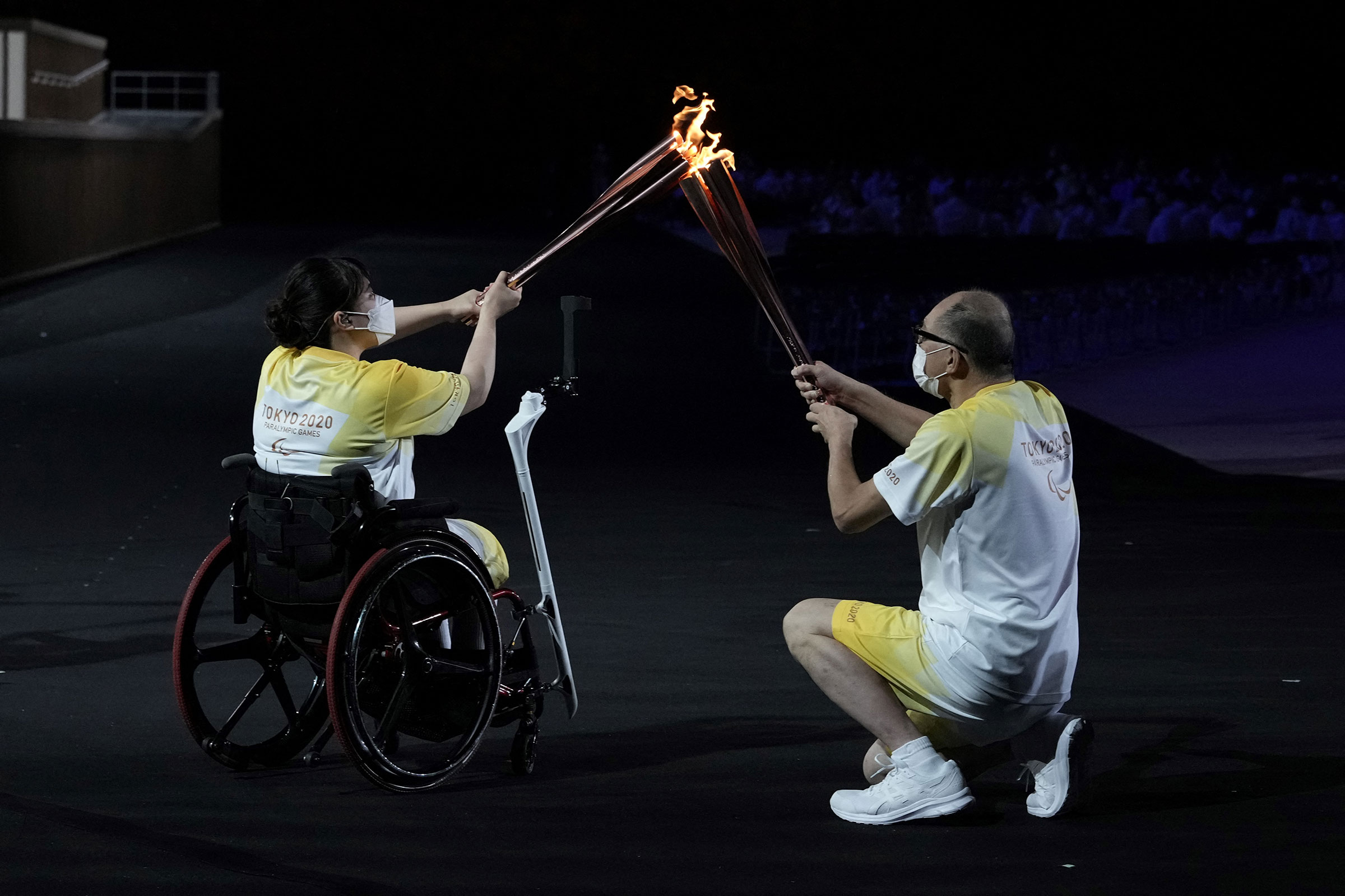 The Paralympic flame is passed between torchbearers during the opening ceremony for the Tokyo 2020 Paralympic Games at the Olympic Stadium in Tokyo on August 24, 2021. (Yasuyoshi Chiba—AFP/Getty Images)