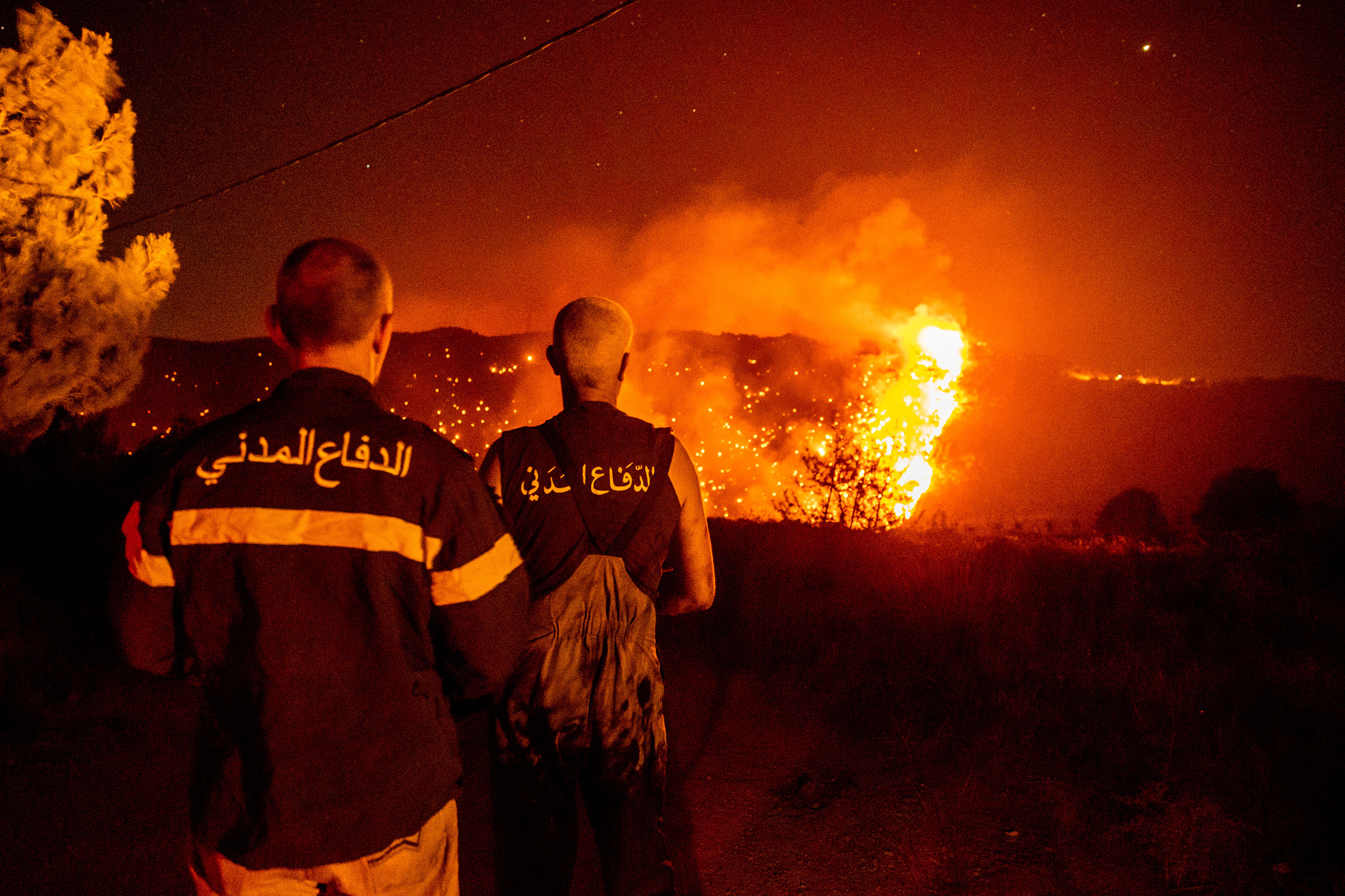 Civil Defense personnel monitor a wildfire burning through hills on July 28 in Qobayat, Lebanon. A Lebanese teenager was killed as he joined volunteers battling to fight the fire.