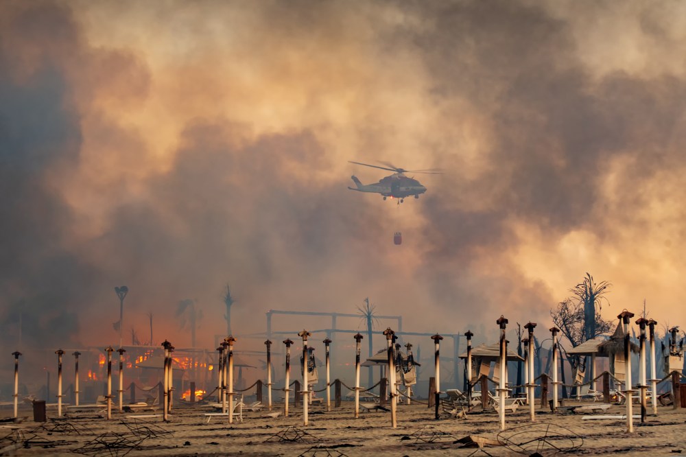 A helicopter flies above a fire at Le Capannine beach in Catania, Sicily, Italy, July 30.