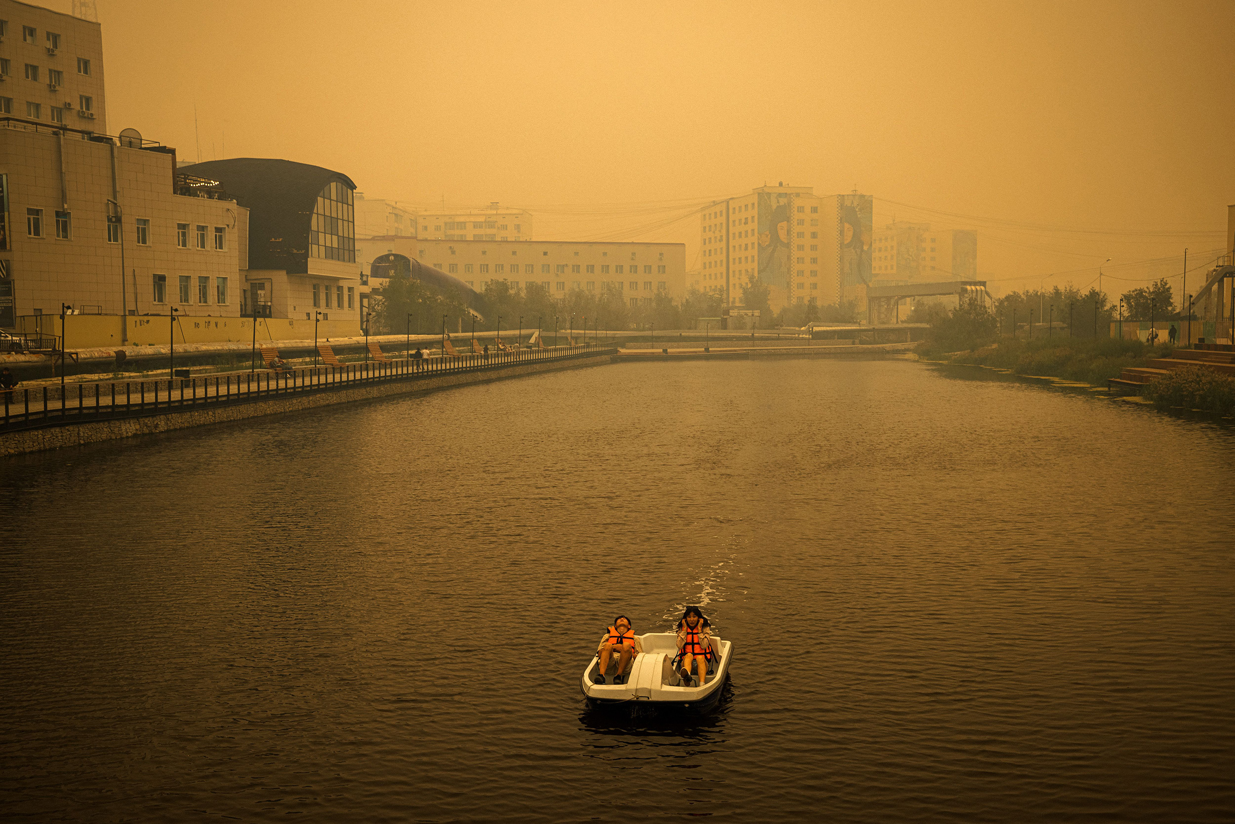 A couple rides a pedal boat as smoke from nearby forest fires hangs over the city of Yakutsk, in Sakha (Yakutia), Russia on July 27.