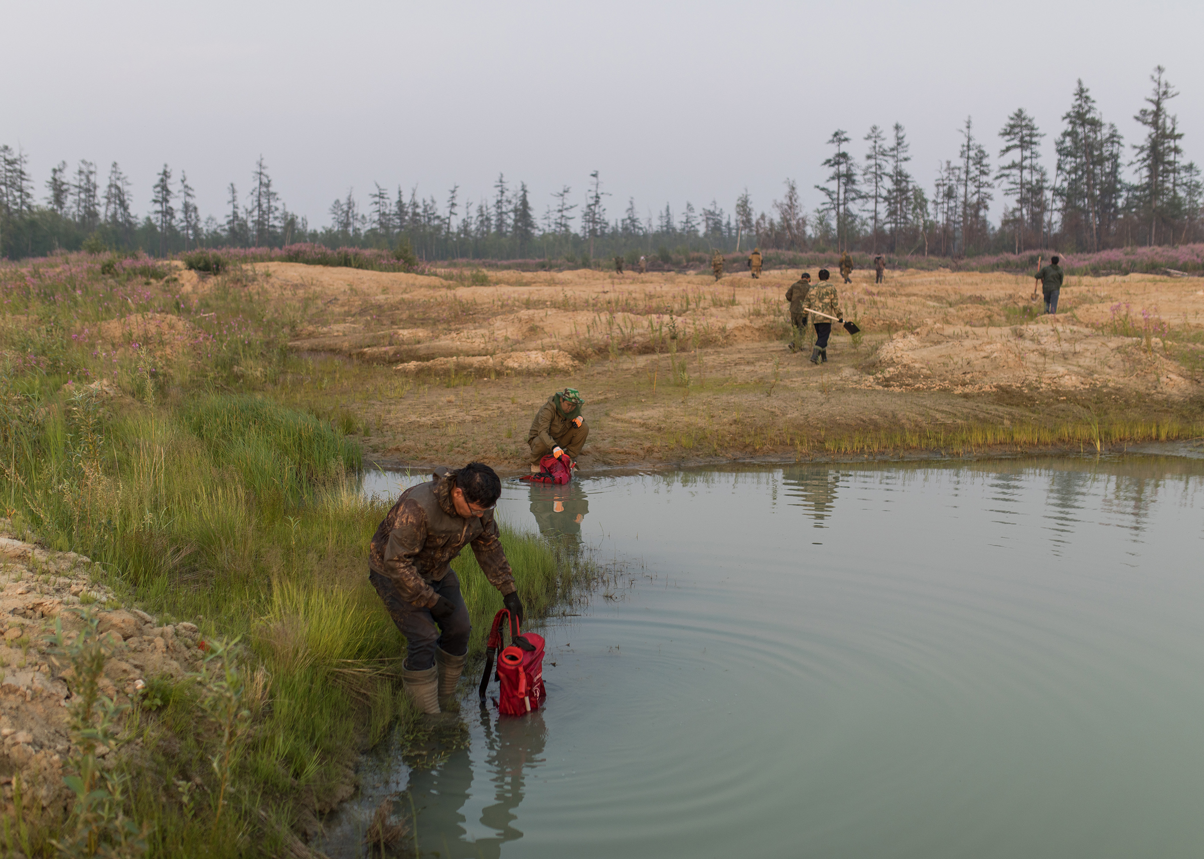 Volunteers fill firefighting satchels with water, at a source near Magaras. (Alexey Vasilyev)