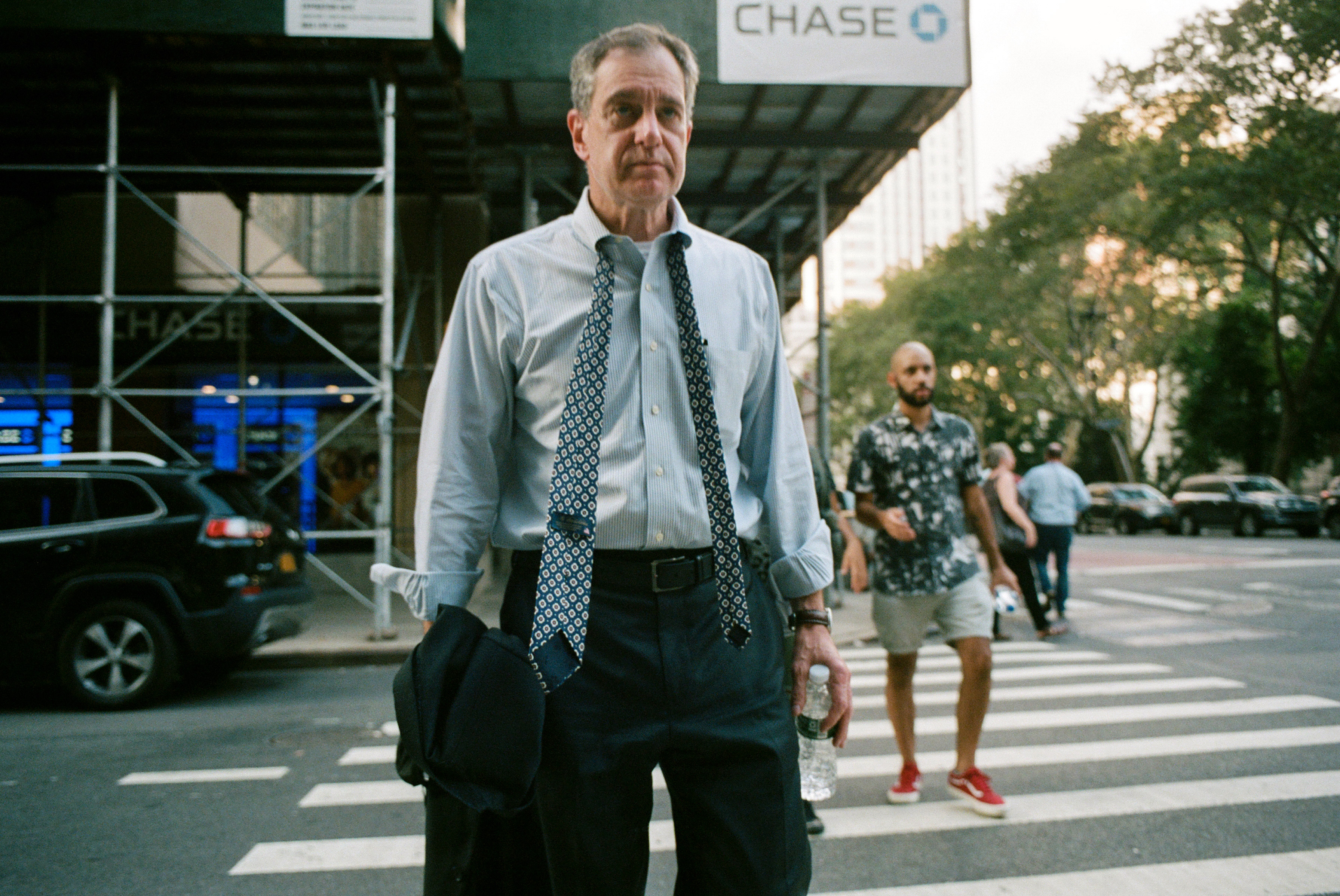 A man with his tie unfurled crosses the street in downtown Manhattan, Aug. 26, 2021. (Daniel Arnold for TIME)