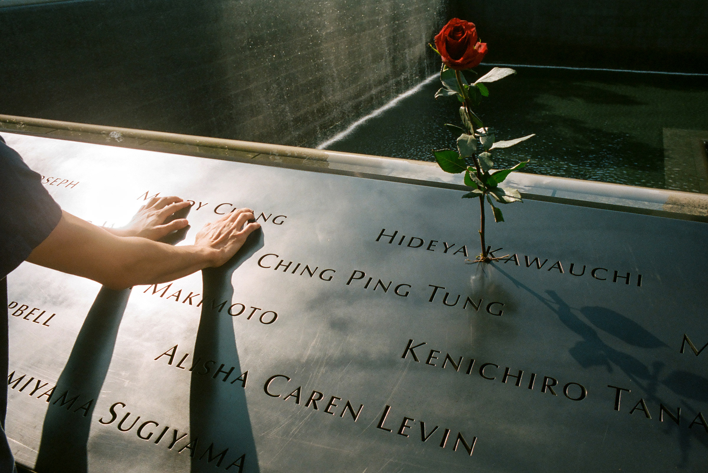 A mourner clings to the name of a lost loved one at the 9/11 memorial, Sept. 11, 2020. (Daniel Arnold)