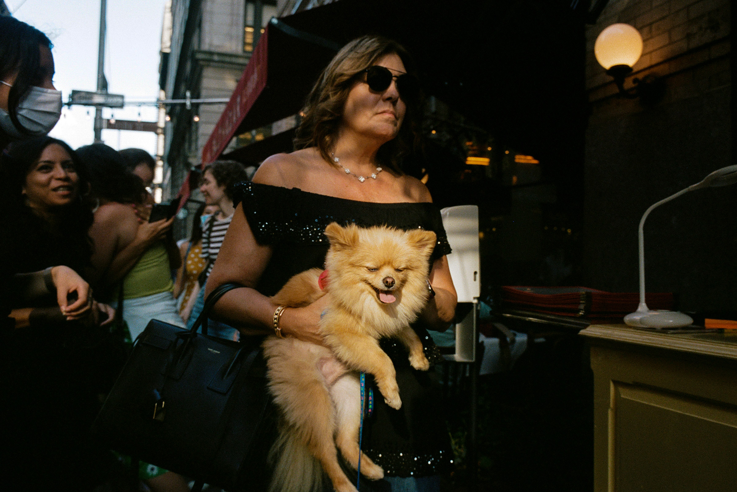 A woman carries her Pomeranian past Balthazar at sunset on Spring Street, Aug. 1, 2021. (Daniel Arnold)