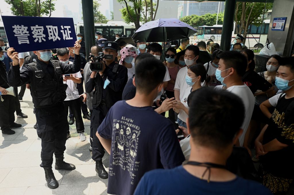Police officers survey people gathering at the Evergrande headquarters in Shenzhen, China on Sept. 16, 2021, as the Chinese property giant said it was facing 