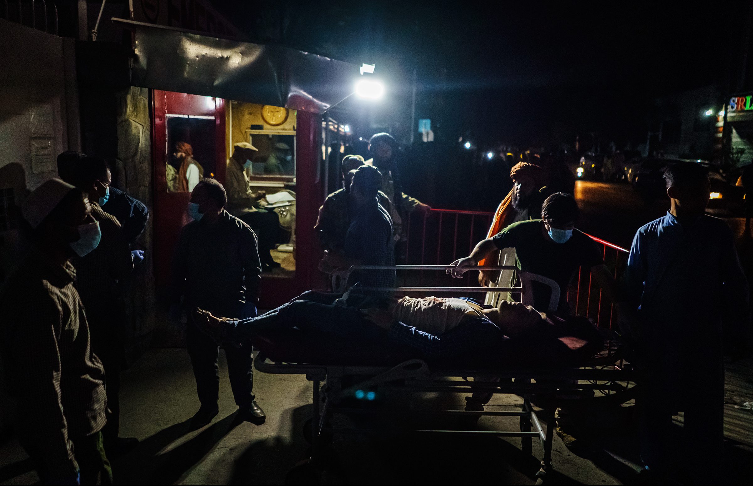 Hospital staff help bring in a wounded patient brought by an ambulance at an emergency hospital in Kabul, Aug. 26. Twin bombings struck near the entrance to Kabul's airport on Thursday. (Marcus Yam—Los Angeles Times/Getty Images)