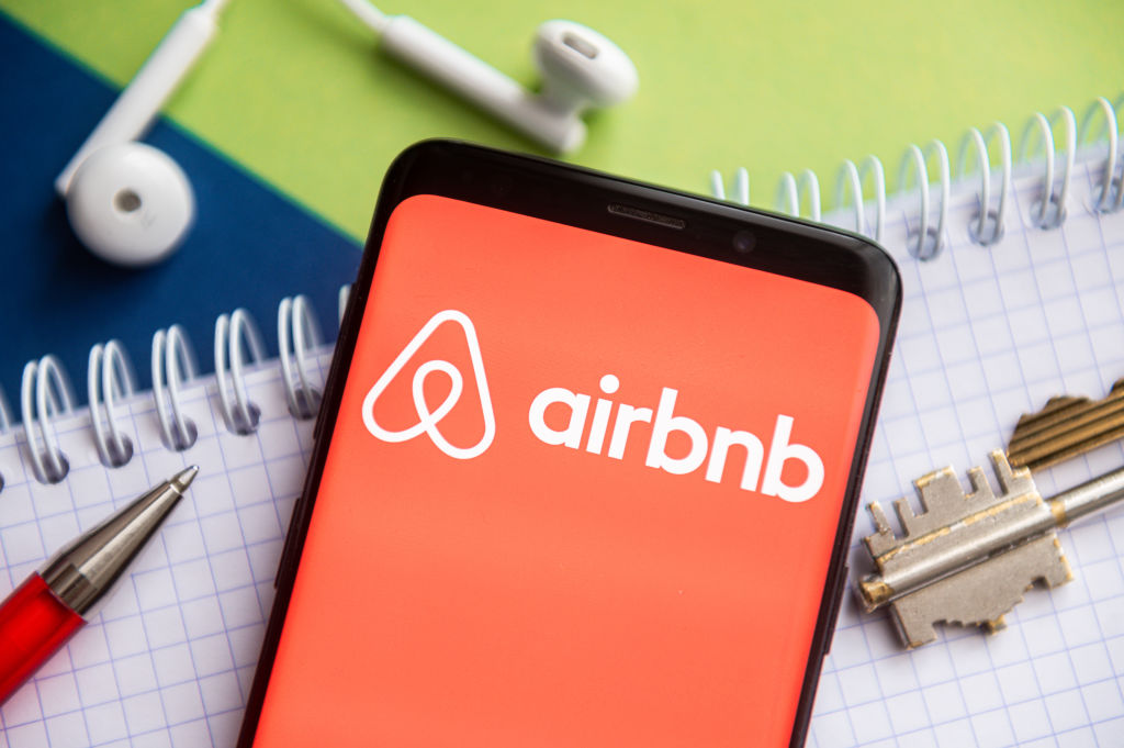 In this photo illustration, an Airbnb logo is seen displayed on a smartphone with a pen, key, book and headsets in the background. (Mateusz Slodkowski—SOPA Images/LightRocket/Getty Images)