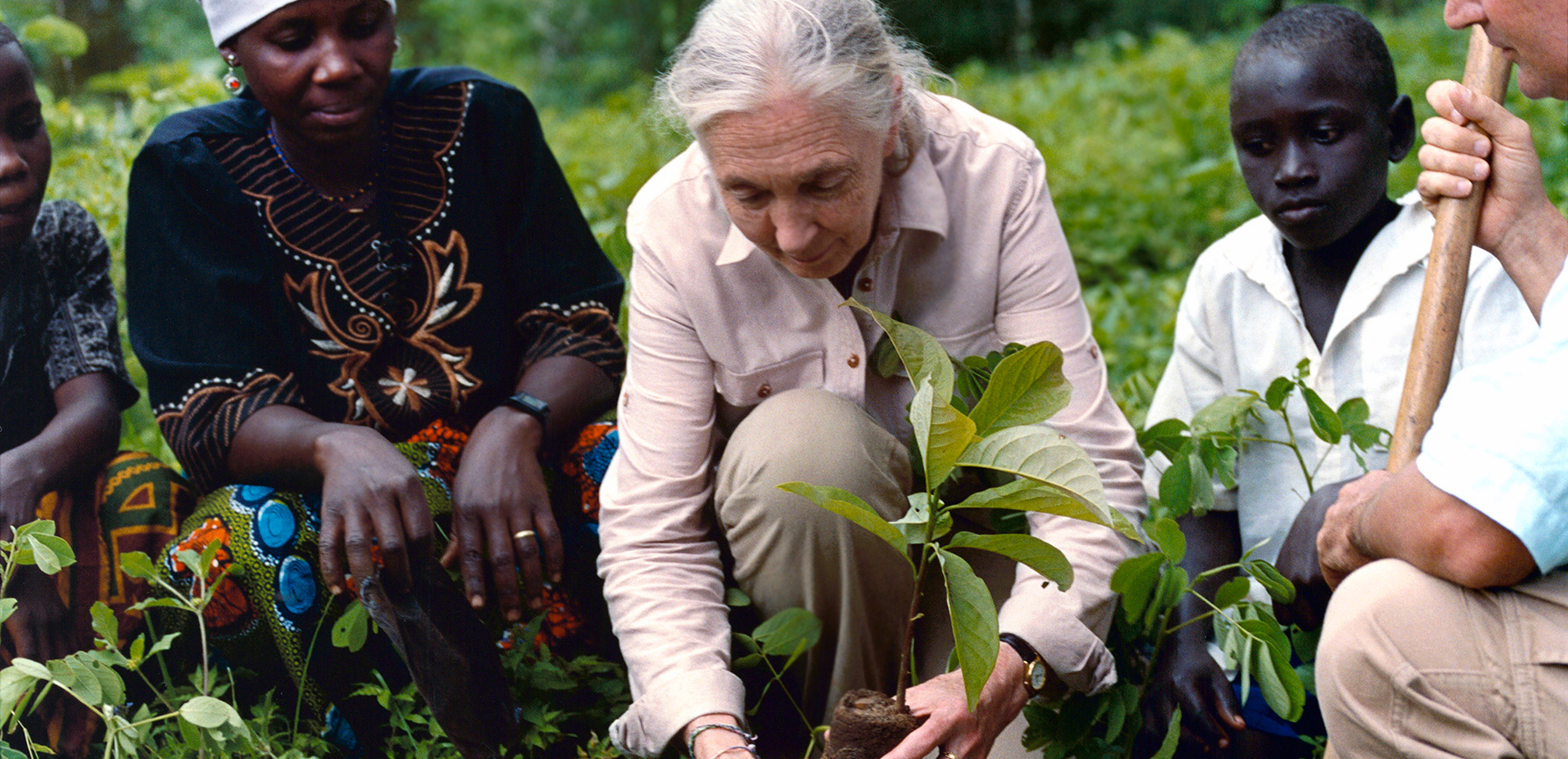Jane Goodall (center) plants a tree seedling