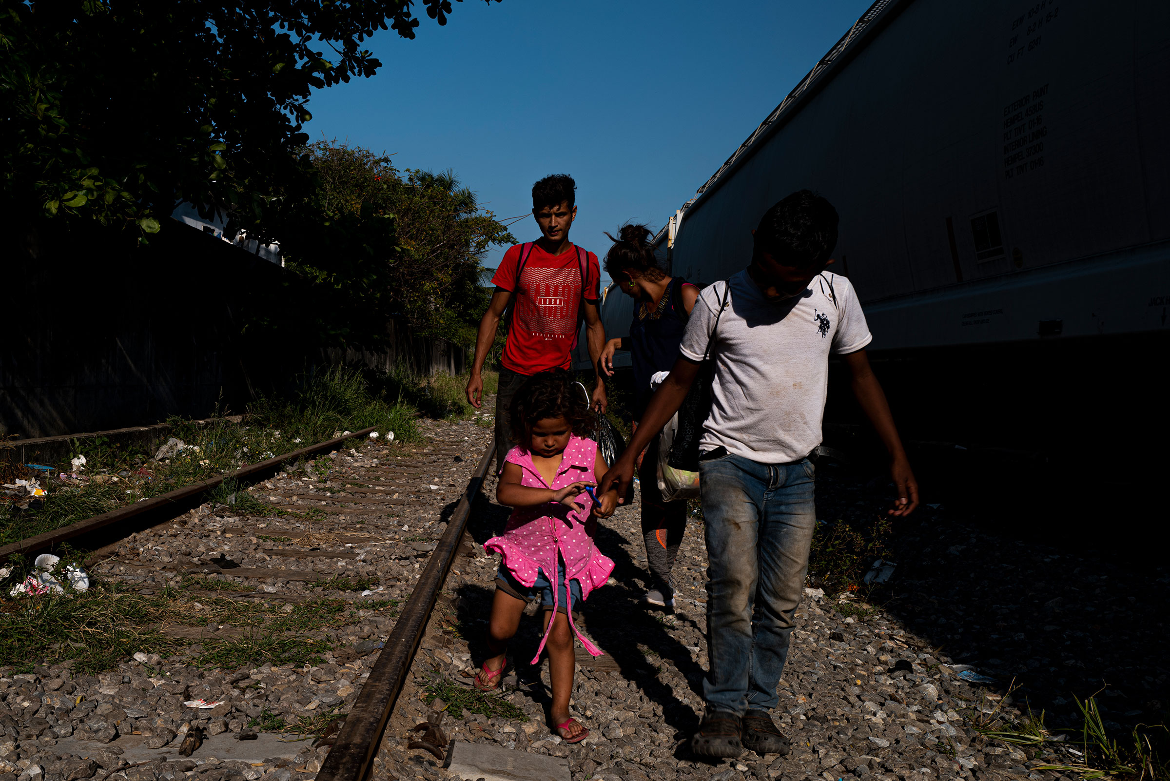 Members of the Ramirez family walk along train tracks in Coatzacoalcos in the Mexican state of Veracruz on March 23, 2021. They fled their home in Santa Barbara, Honduras after their lives were threatened by gang members. Erica Ramirez is nine months pregnant. (Yael Martínez—Magnum Photos for TIME)