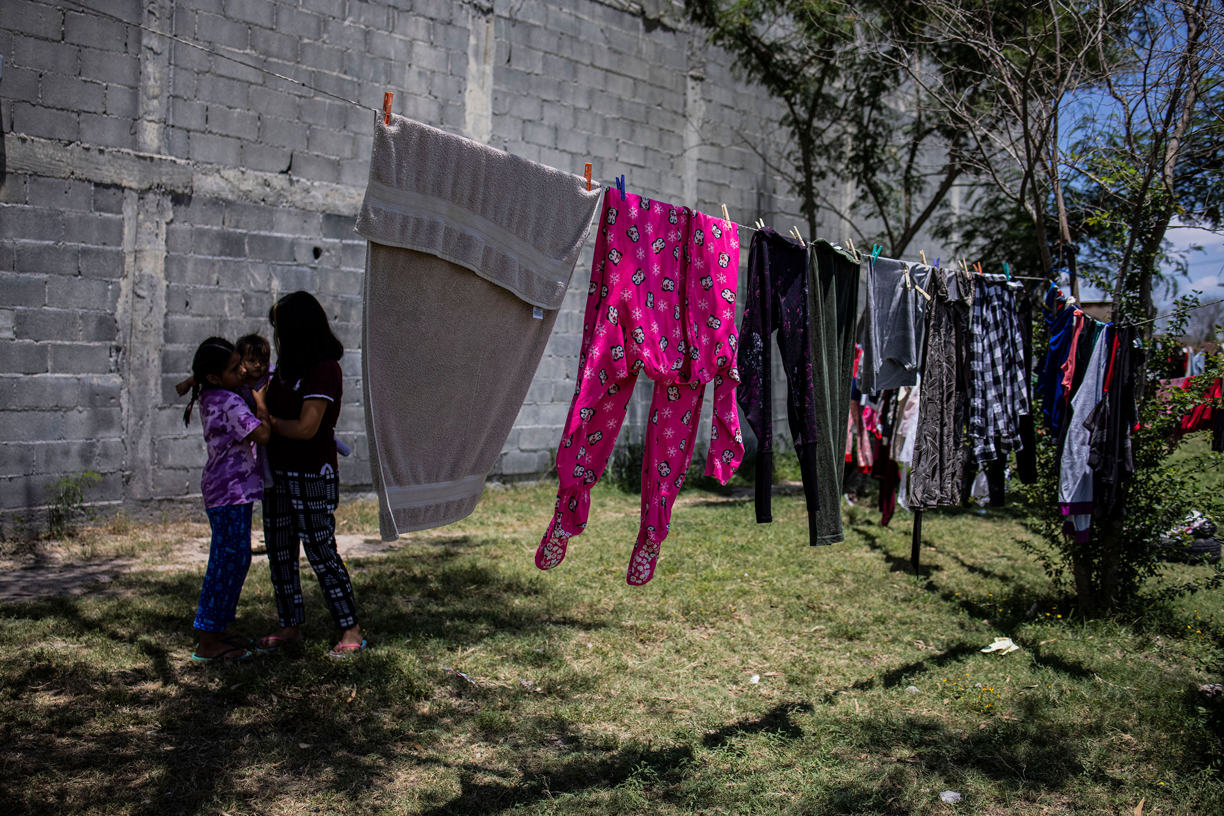 The Palma family spend time near clotheslines at the Viento Recio church in Matamoros in the Mexican state of Tamaulipas on May 7, 2021. They fled the Mexican state of Guerrero after receiving death threats from an organized crime group. (Yael Martinez—Magnum Photos for TIME)