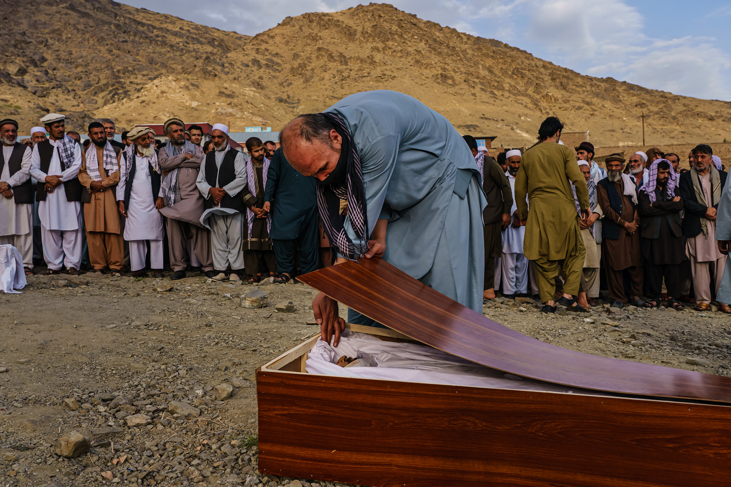 A man bids farewell to Zamarai Ahmadi in his casket during a mass funeral in Kabul on Aug. 30, 2021.