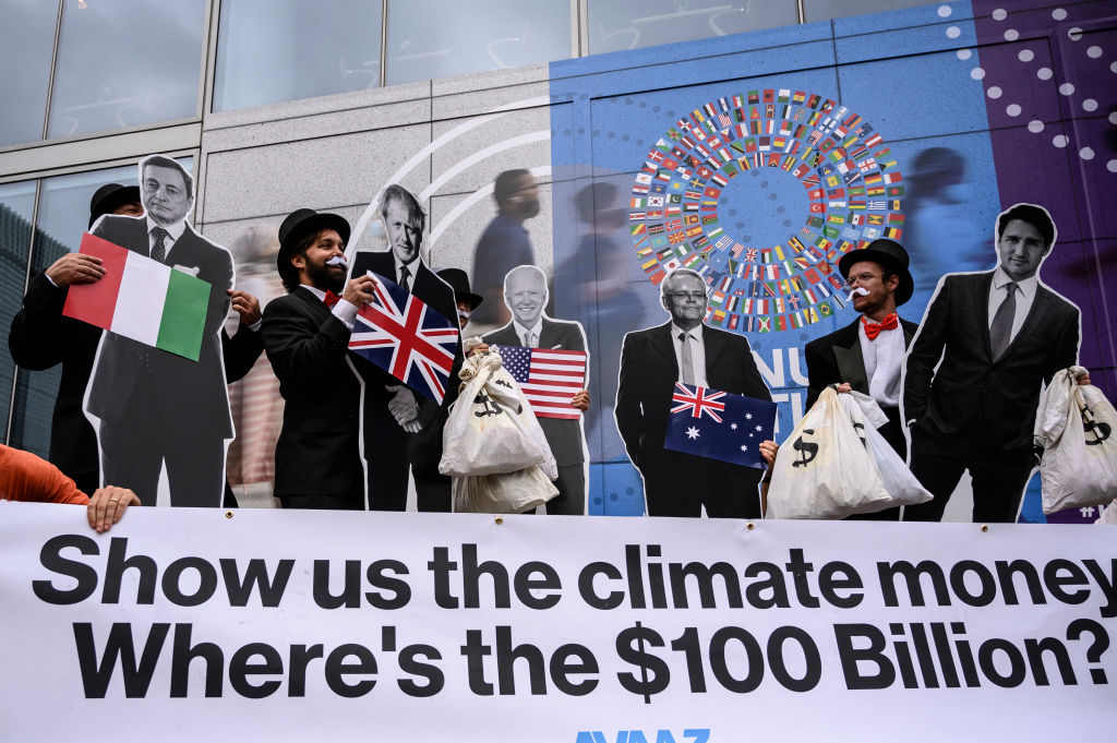 Activists dressed as debt collectors" hold cutouts of the leaders of Italy, U.K., the U.S., Australia and Canada during a demonstration in front of the International Monetary Fund headquarters in Washington D.C. to ask rich nations to keep their commitment to support developing countries to tackle climate change on October 13, 2021. (Pedro Ugarte—AFP/Getty Images)