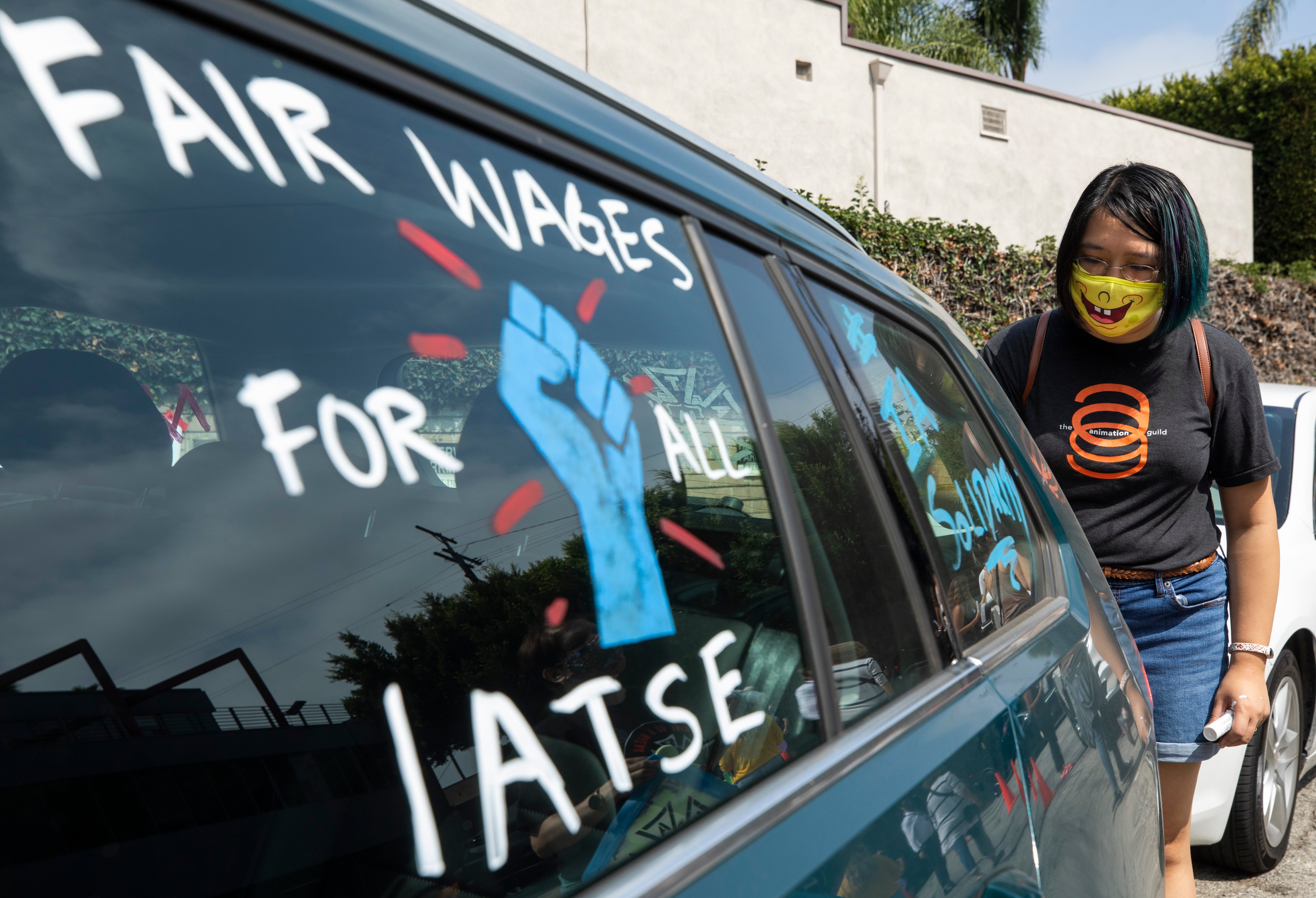 Crystal Kan, a storyboard artist, draws pro-labor signs on cars of union members during a rally at the Motion Picture Editors Guild IATSE Local 700 on Sunday, Sept. 26, 2021 in Los Angeles, CA (Myung J. Chun—Los Angeles Times/Getty Images)