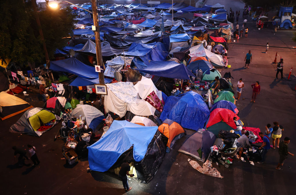 Asylum-seeking migrants gather at a makeshift camp on the Mexican side of the San Ysidro Port of Entry on July 20, 2021 in Tijuana, Mexico. (Mario Tama/Getty Images)