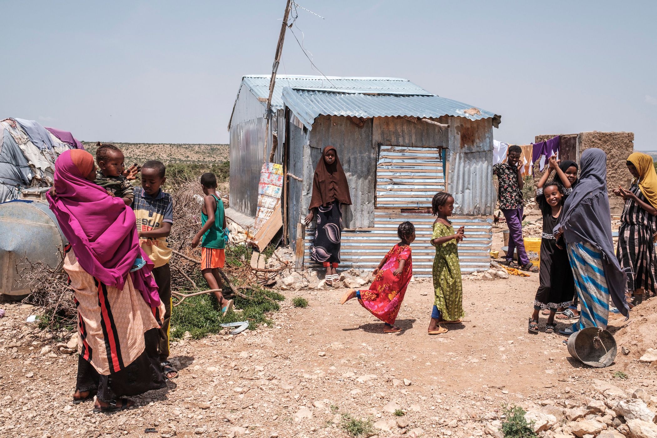 People stand outside of their homes in an informal settlement of internally displaced people in the outskirts of the city of Hargeisa, Somaliland, on September 16, 2021.