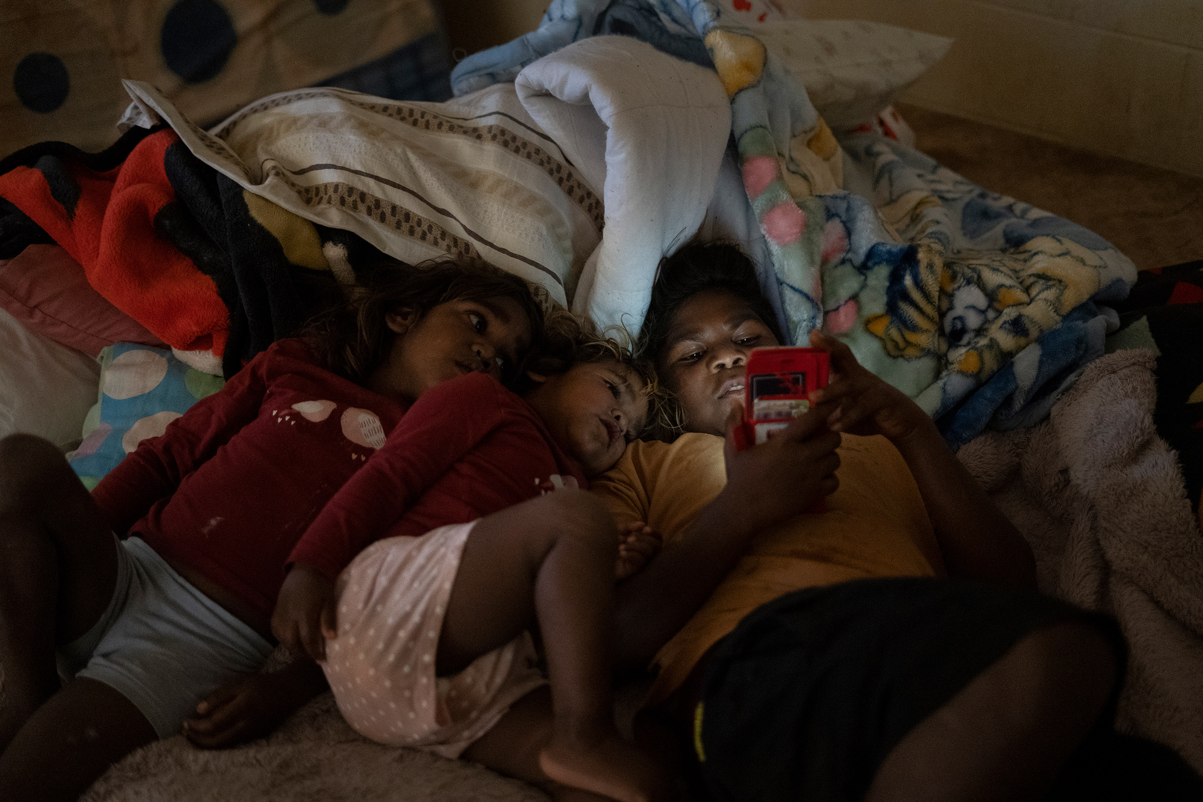 Norman Frank’s daughter Neetu, Nina and grandson Ashuan sit in the dark in order to conserve energy in his home in Tennant Creek