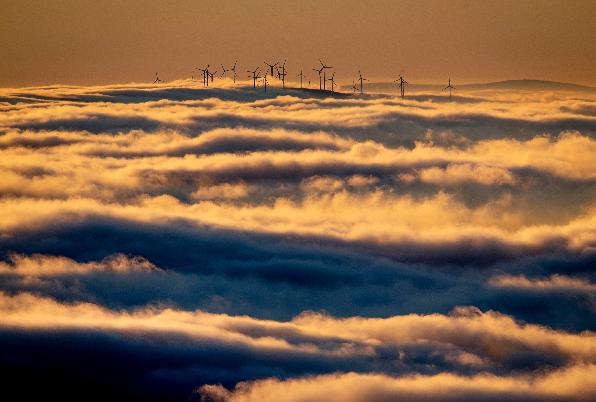 Wind turbines on a hill are surrounded by fog and clouds near Frankfurt in Jan. 6, 2020. (Michael Probst—AP)
