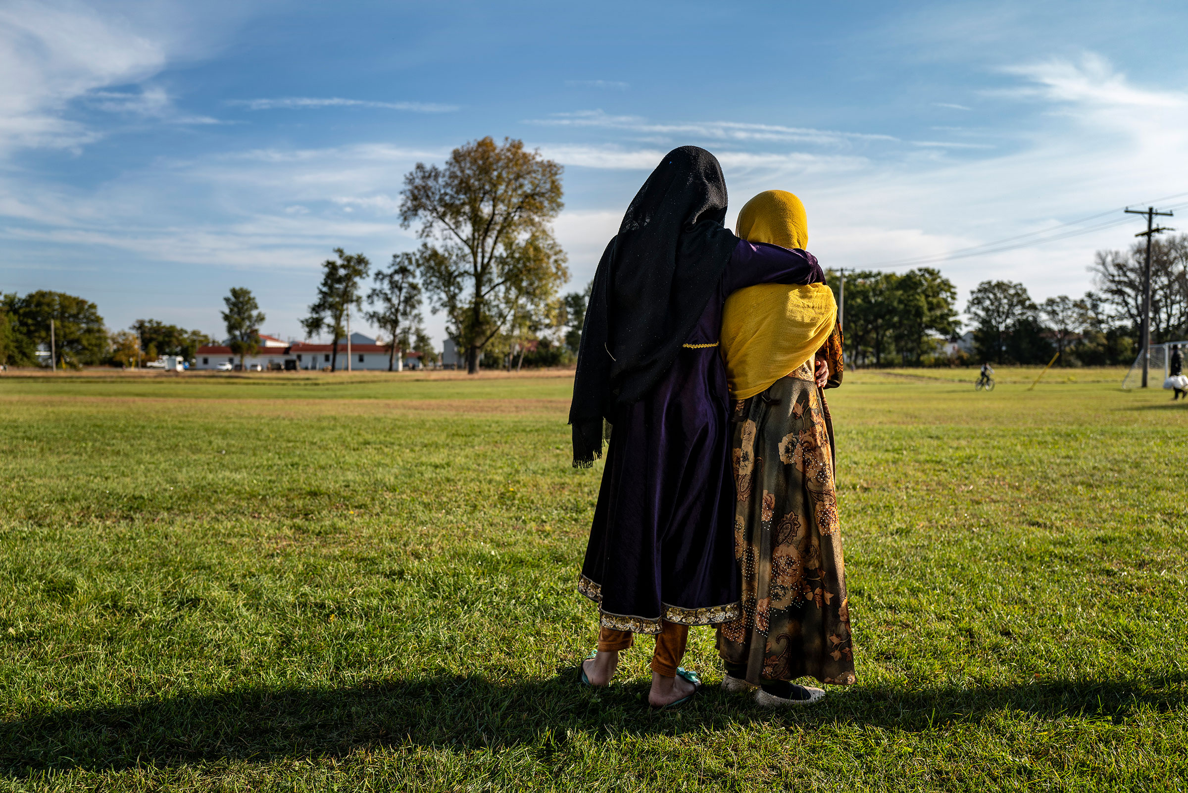 Afghan refugee girls watch a soccer match near where they are staying in the Village at the Ft. McCoy U.S. Army base on September 30, 2021 in Ft. McCoy, Wisconsin. There are approximately 12,600 Afghan refugees at the base under Operation Allies Welcome. (Barbara Davidson—Getty Images)