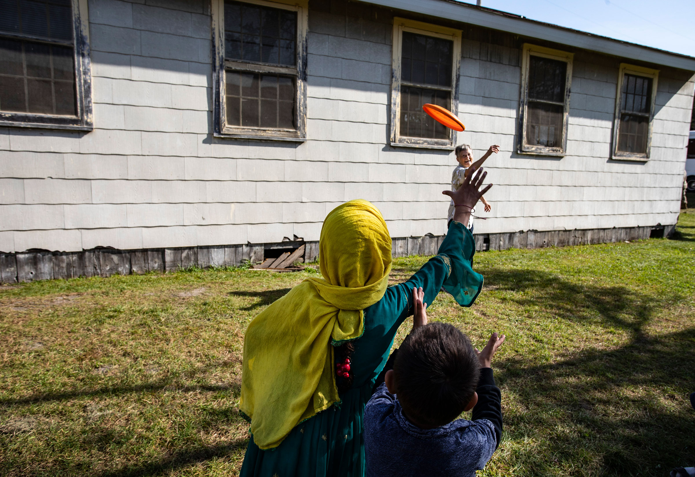 Volunteer Sandra Hoeser plays frisbee with Afghan refugees at the Ft. McCoy U.S. Army base on September 30, 2021 in Ft. McCoy, Wisconsin. (Barbara Davidson—Getty Images)
