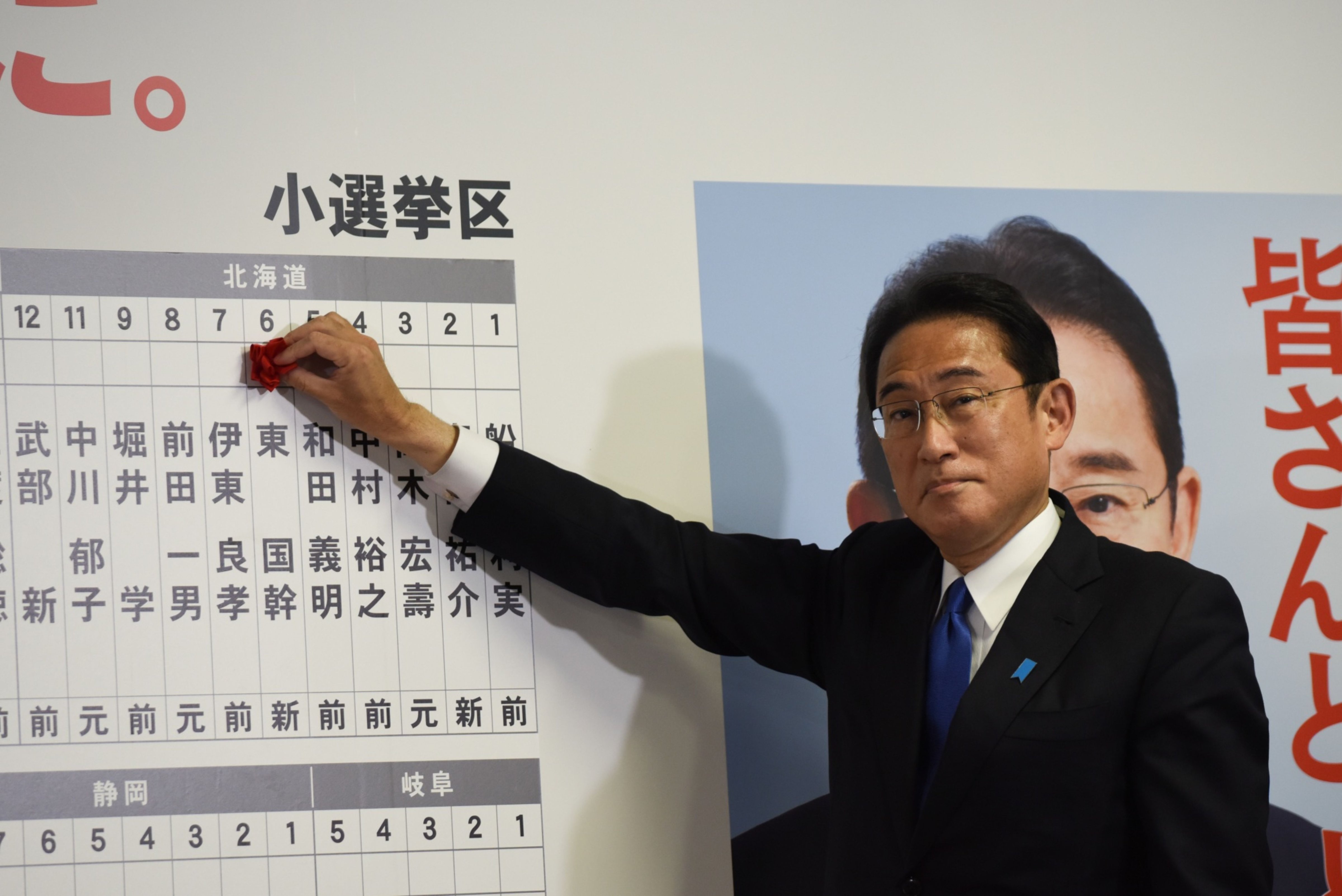 Fumio Kishida places a red paper rose on a LDP candidate's name to indicate an election victory on Oct. 31. (© 2021 Bloomberg Finance LP)