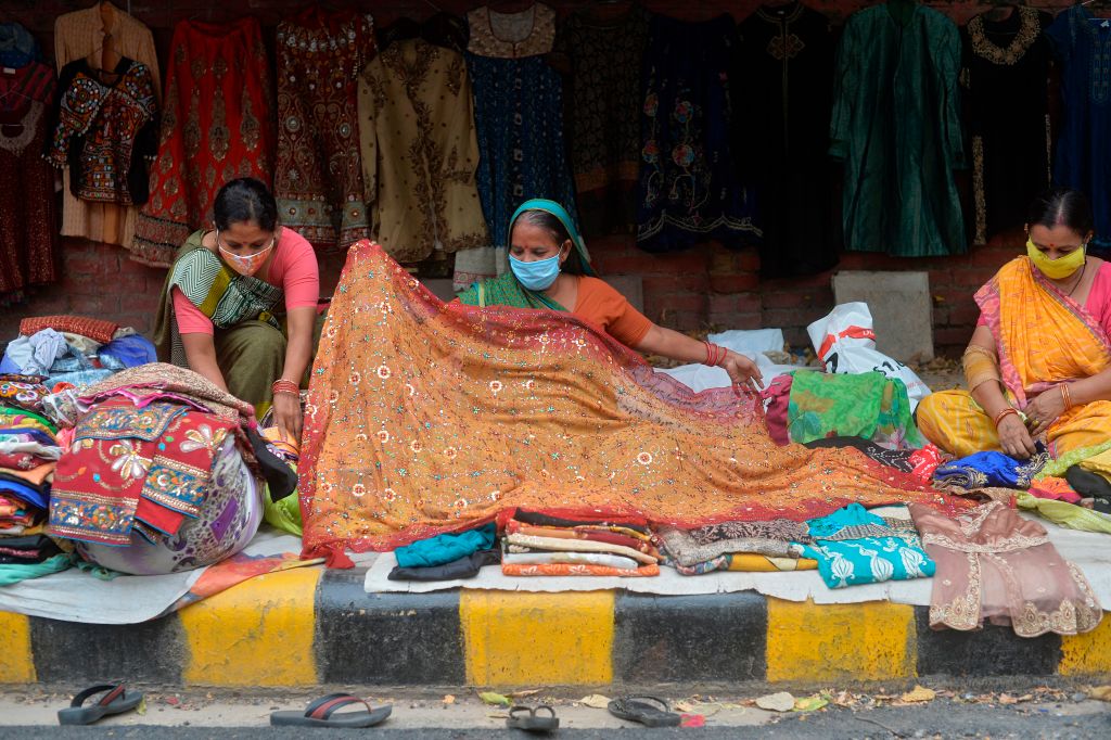 Women vendors wearing facemasks as a preventive measure against the Covid-19 coronavirus, work at their roadside shop selling sarees, in New Delhi on September 26, 2020. (Sajjad Hussain—AFP/Getty Images)