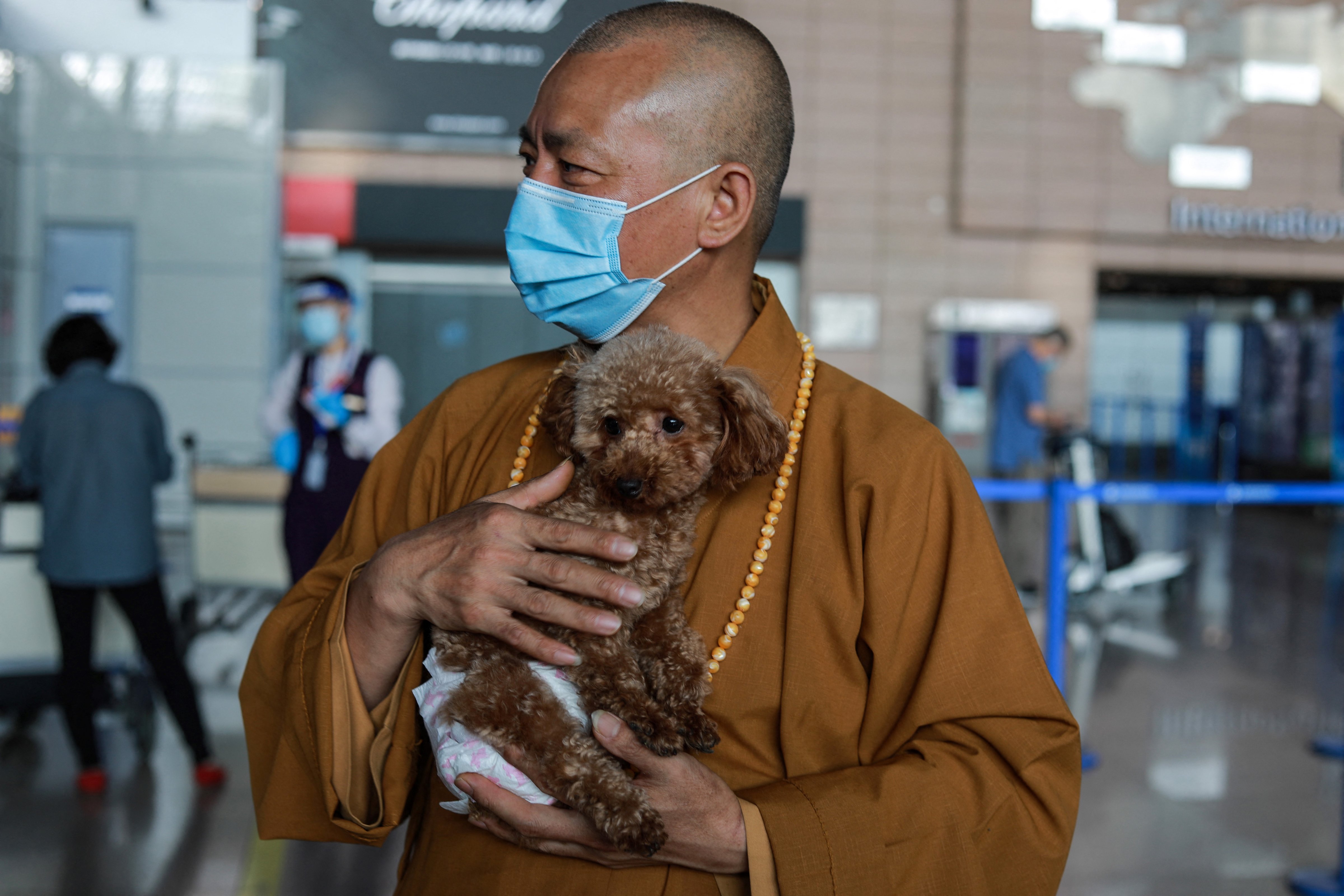 Zhi Xiang, a Buddhist monk who helps care for and find homes for stray animals in China, carries a dog destined for a home in the U.S. at the airport in Shanghai, on May 26, 2021. New CDC rules have made it harder to transport dogs into the United States. (Jessica Yang—AFP/Getty Images)