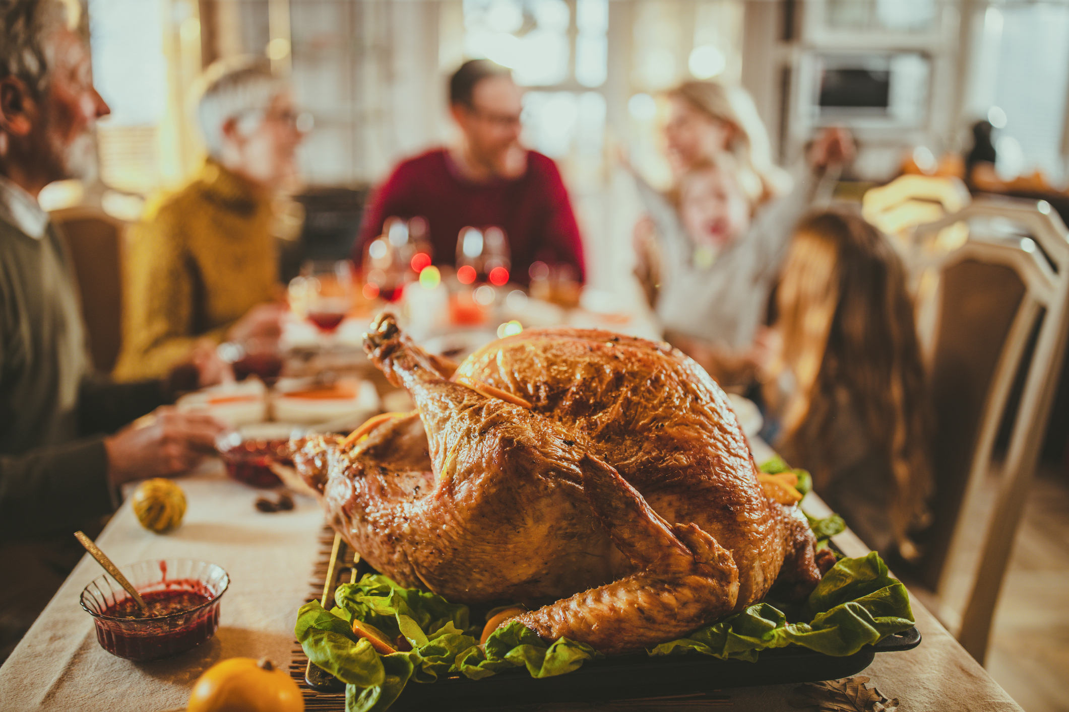 Close up of Thanksgiving stuffed turkey on dining table with family in the background. (skynesher)