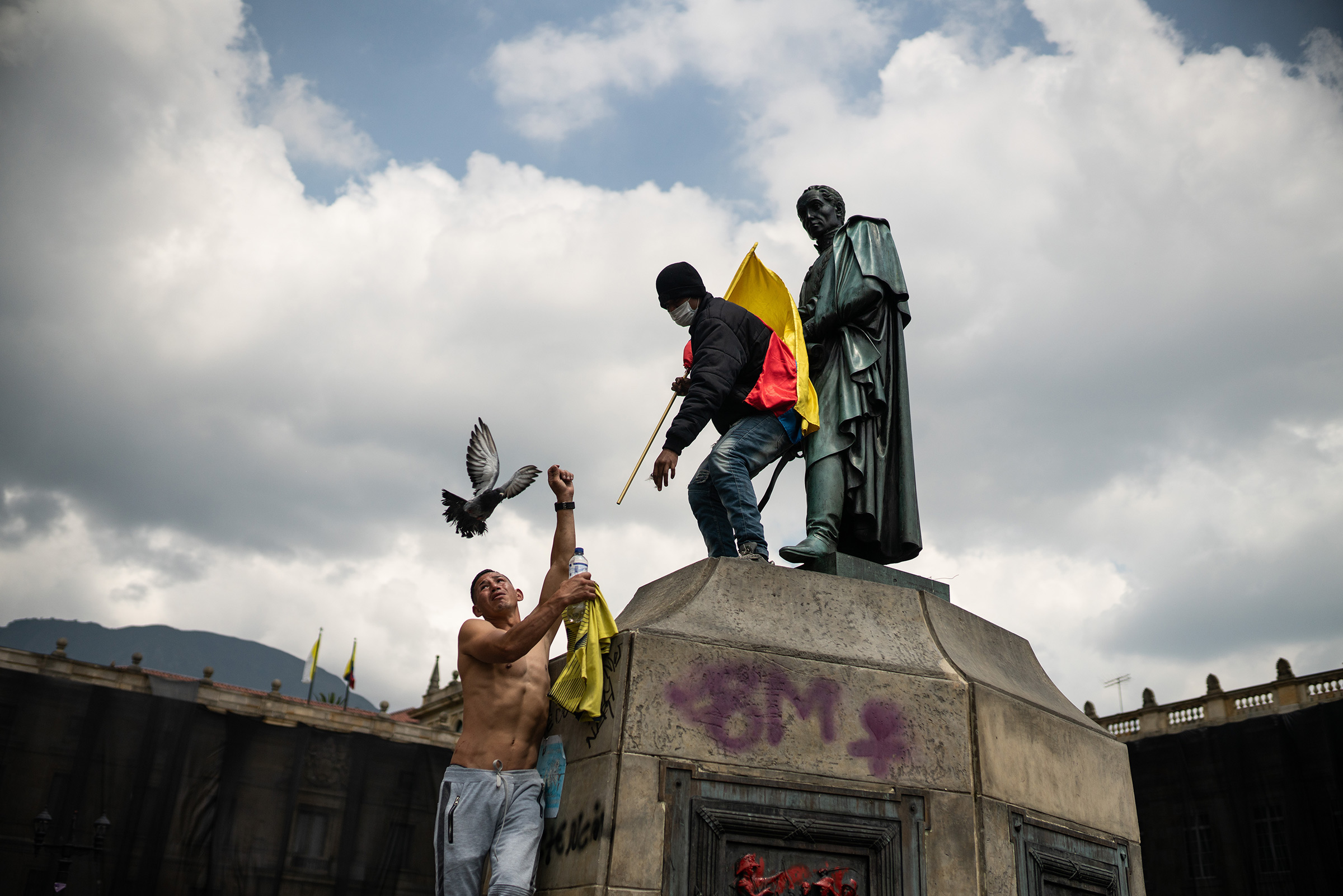 Protesters climb on the statue of Simón Bolívar, the South American independence leader and former president of Colombia, as thousands of Colombians take to the streets to protest against the government's tax reform in Bogotá on May 1.