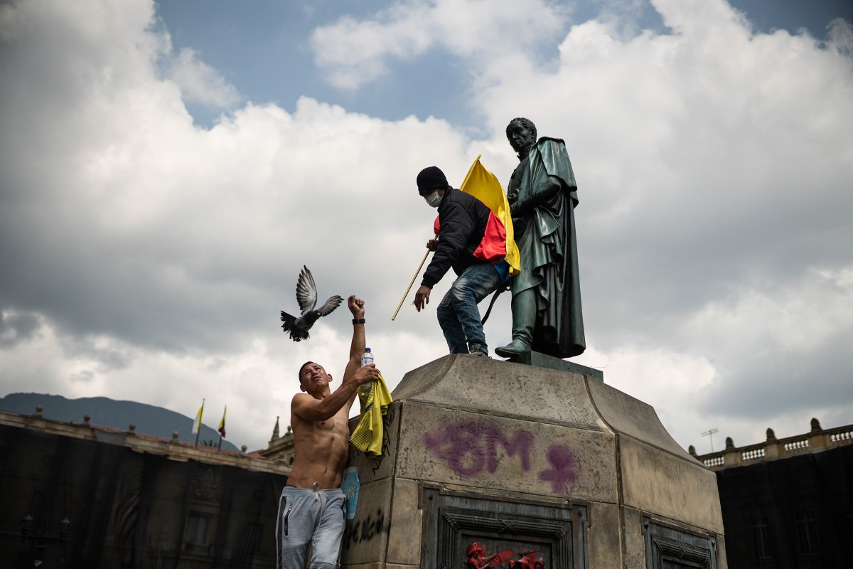 Protesters climb on the statue of SimÃ³n BolÃ­var, the South American independence leader and former president of Colombia, as thousands of Colombians take to the streets to protest against the government's tax reform in BogotÃ¡ on May 1.