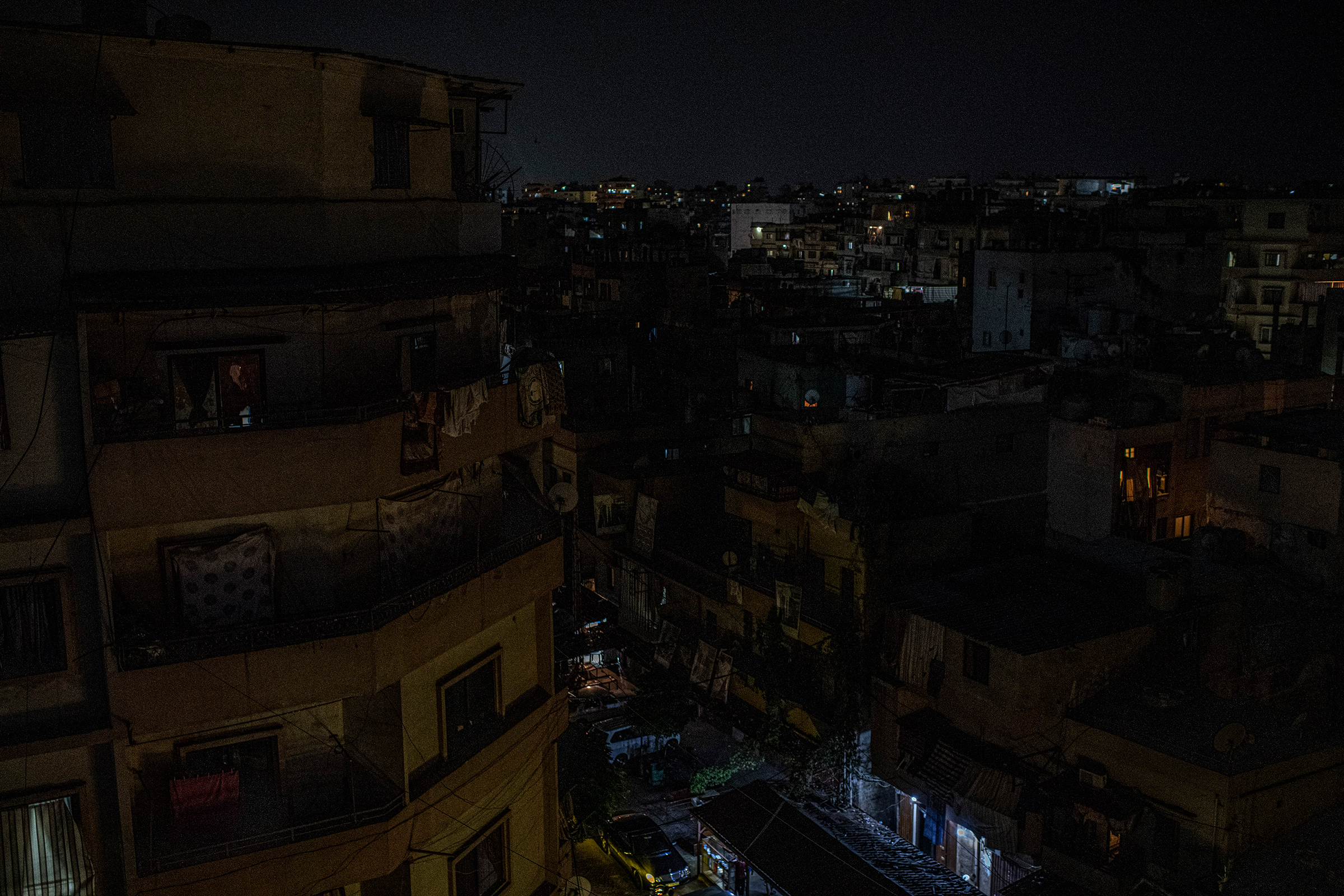 Small spots of light indicate who can still afford to pay for private electricity generation in the Bab al-Tabaneh neighborhood of Tripoli, Lebanon, on July 8. A financial collapse that could rank among the world's worst since the mid-1800s is closing like a vise on Lebanon's middle class, whose money has plummeted in value as the cost of nearly everything has skyrocketed. (Bryan Denton—The New York Times/Redux)