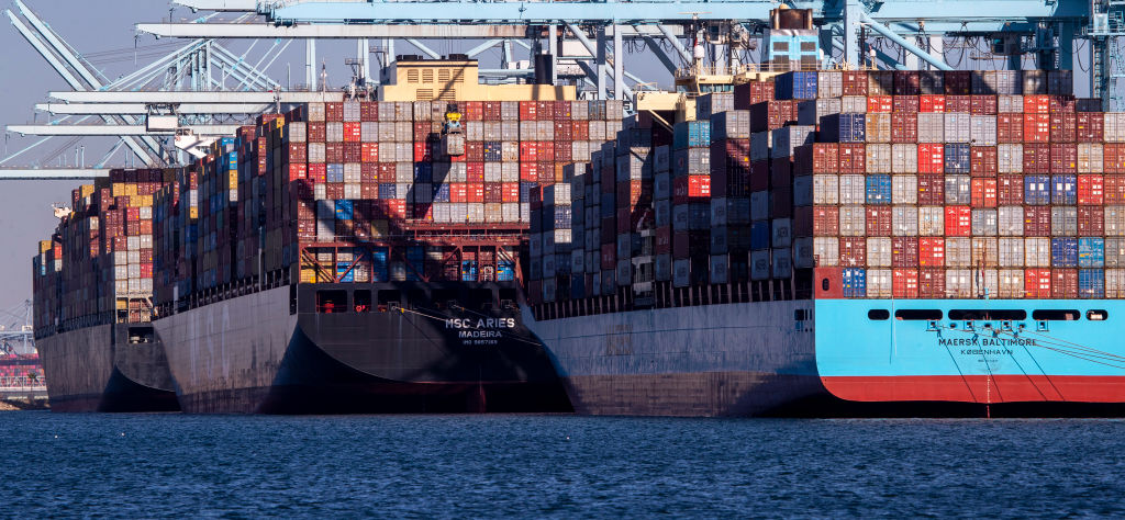 Thousands of containers are unloaded from a ship at the Ports of Los Angeles and Long Beach, while dozens of large container ships wait to be unloaded offshore. (Allen J. Schaben / Los Angeles Times via Getty Images)