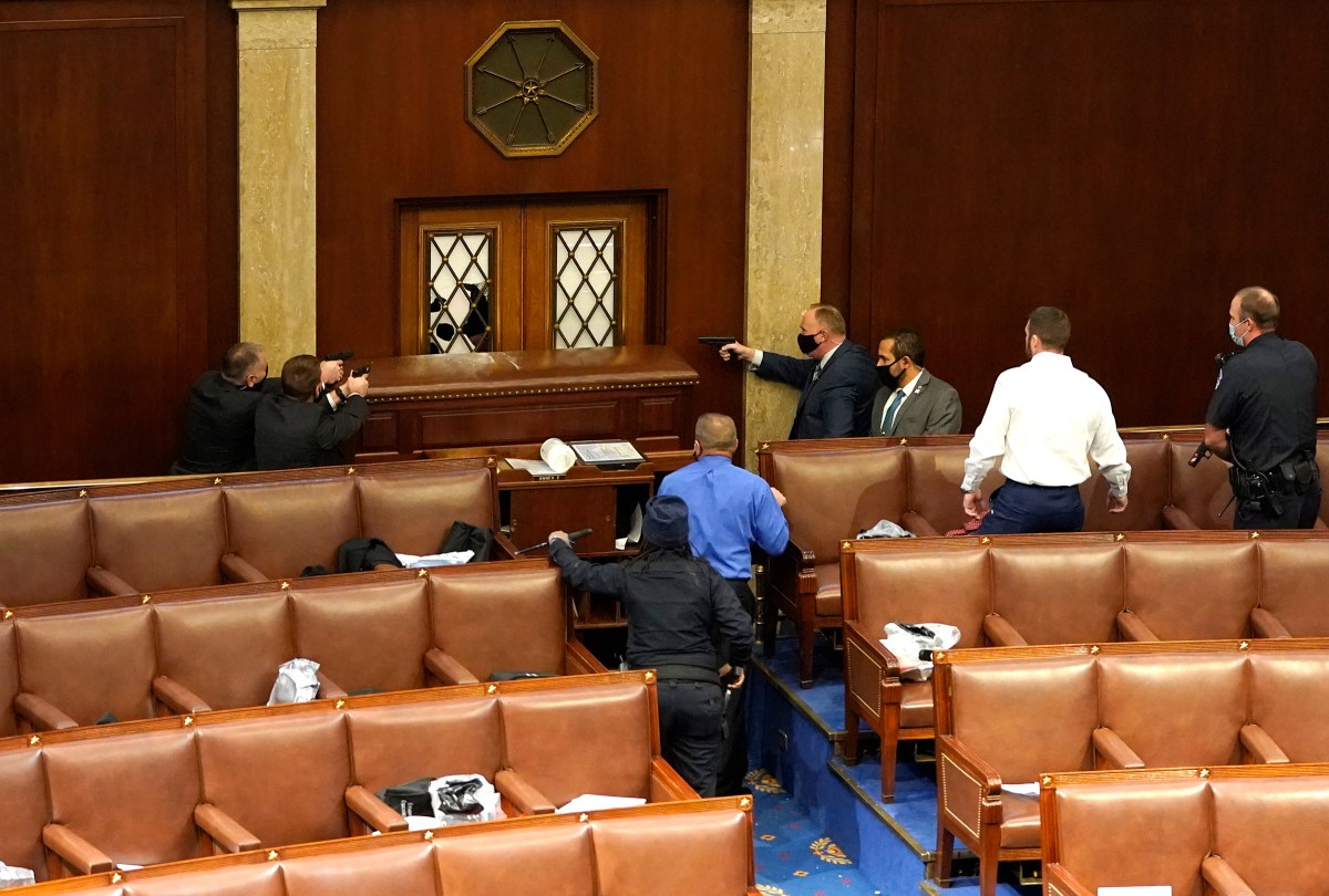 Officers draw their weapons in the House Chamber during the Jan. 6, 2021, attack on the U.S. Capitol by a mob of President Trump's supporters, who sought to disrupt the certification that day of President-elect Joe Biden's win.