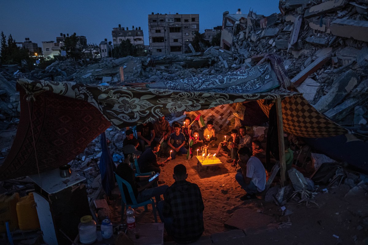 Palestinian children hold candles during a rally amid the ruins of houses destroyed by Israeli airstrikes in Beit Lahia, Gaza, on May 25, 2021. A fragile cease-fire between Israel and Hamas brought an end to 11 days of fighting.