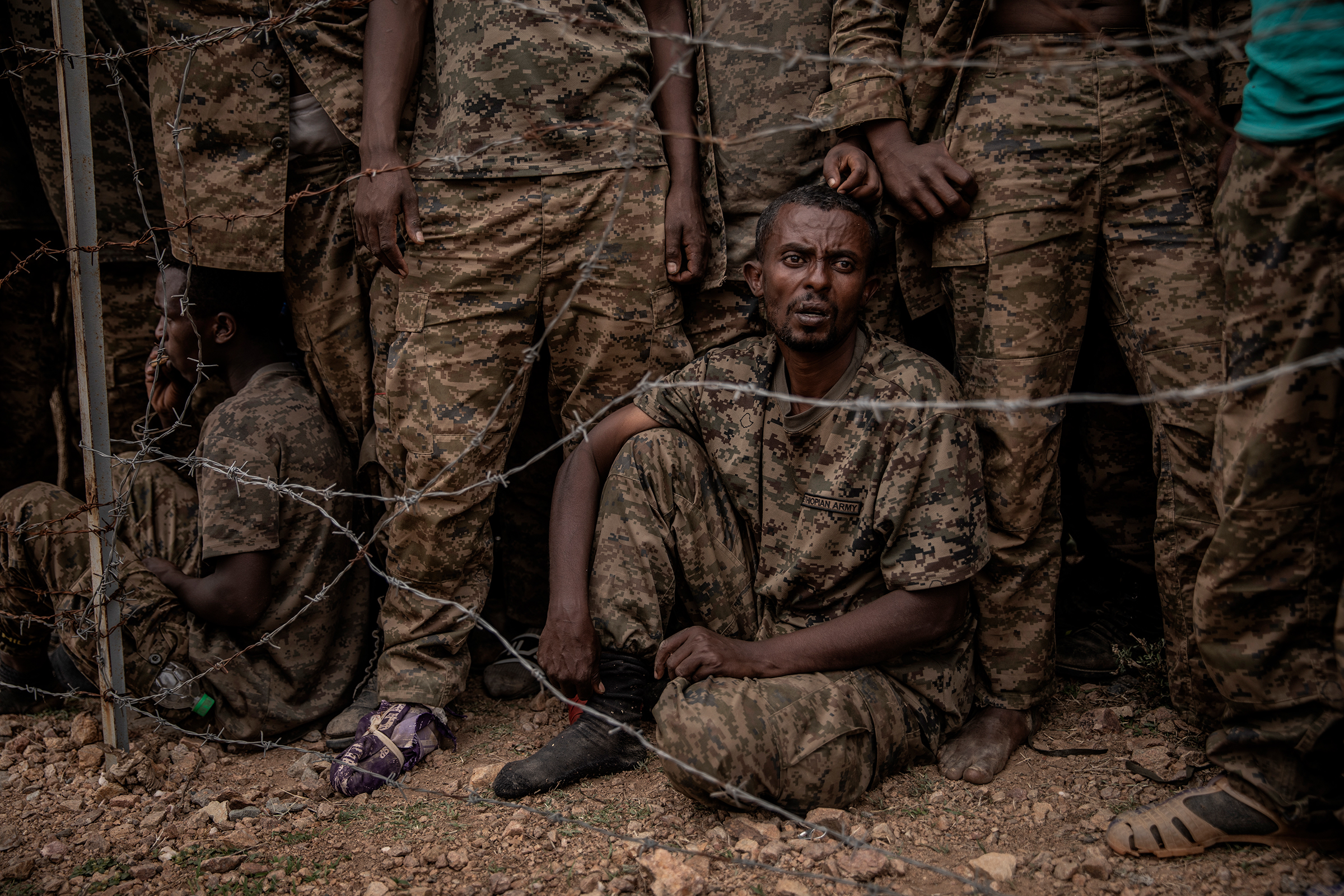 Ethiopian National Defense Forces soldiers are held at a remote mountain detention camp for an estimated 3,000 prisoners of war south of Mekele on June 23, after being captured during fighting the prior week by Tigray Defense Forces rebels. Most of the captured soldiers had their boots confiscated. (Finbarr O'Reilly)