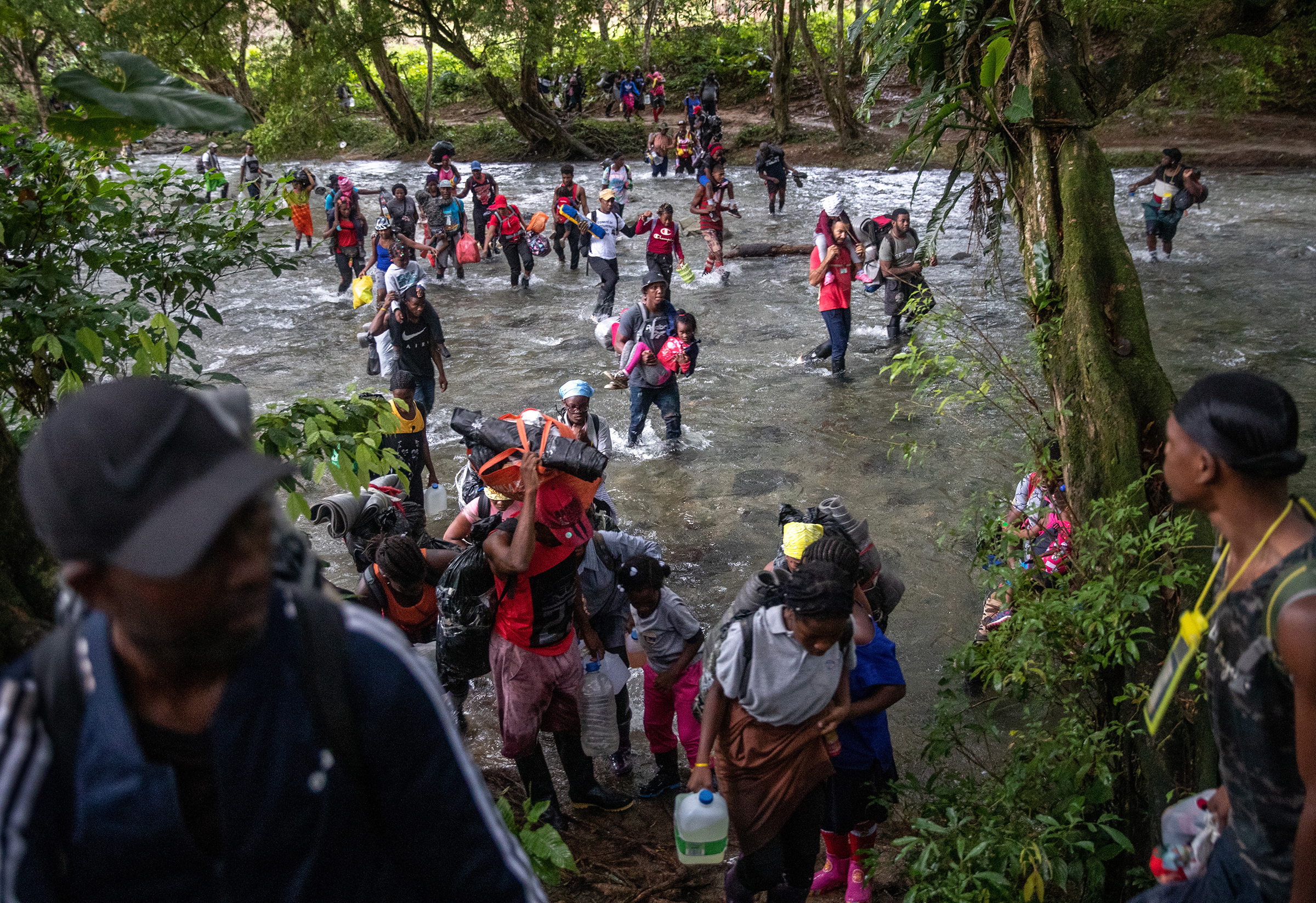 Families, mostly from Haiti, make one of dozens of river crossings on the first day of their trek through the Darién Gap in Colombia on Oct. 18. The 66-mile passage through dense rainforest and mountains is considered the most difficult stretch for migrants traveling from South America to the United States. (John Moore—Getty Images)