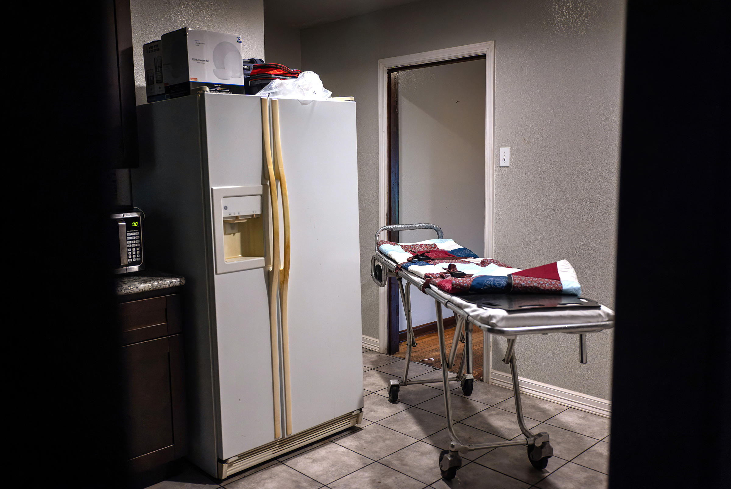 An empty stretcher waits in a kitchen as a funeral home worker prepares to transport the body of a 54-year-old woman who died from COVID-19 in her bed at home in Houston on Sept. 13. The woman's daughter said her mother had not been inoculated, citing fears of the vaccine.