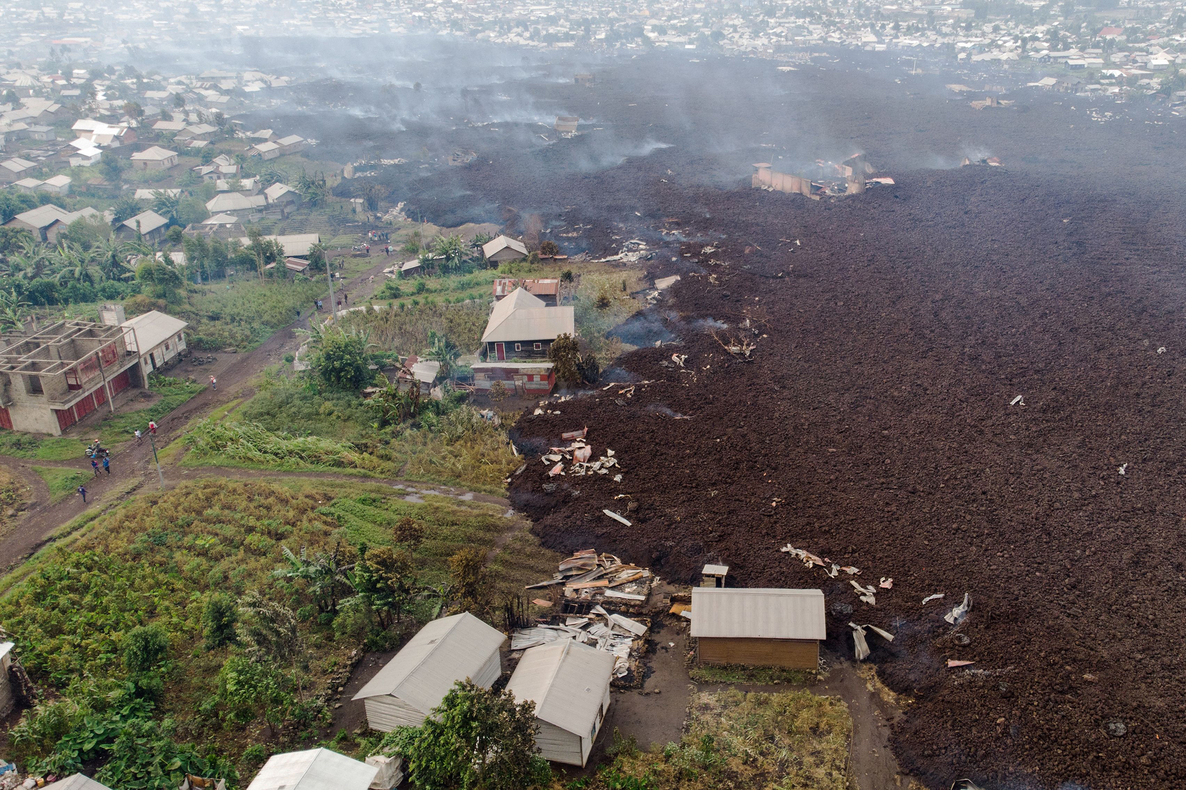 An aerial view shows debris engulfing buildings in Bushara village, near Goma, on May 23, after a volcanic eruption of Mount Nyiragongo that sent thousands of residents fleeing during the night in eastern Democratic Republic of Congo. The river of boiling lava came to a halt outside Goma; five people died in related accidents.