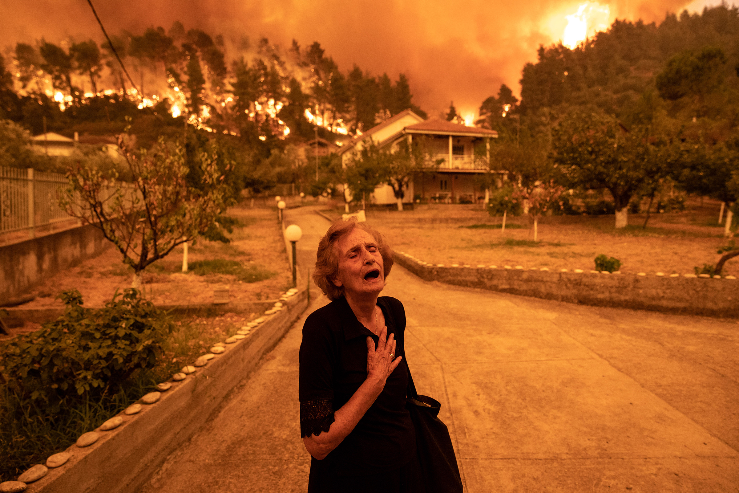 On the Greek island of Evia, wildfires resulting from the country’s worst drought in three decades approach the home of Ritsopi Panayiota, 81, on Aug. 8. (Konstantinos Tsakalidis—Bloomberg/Getty Images)