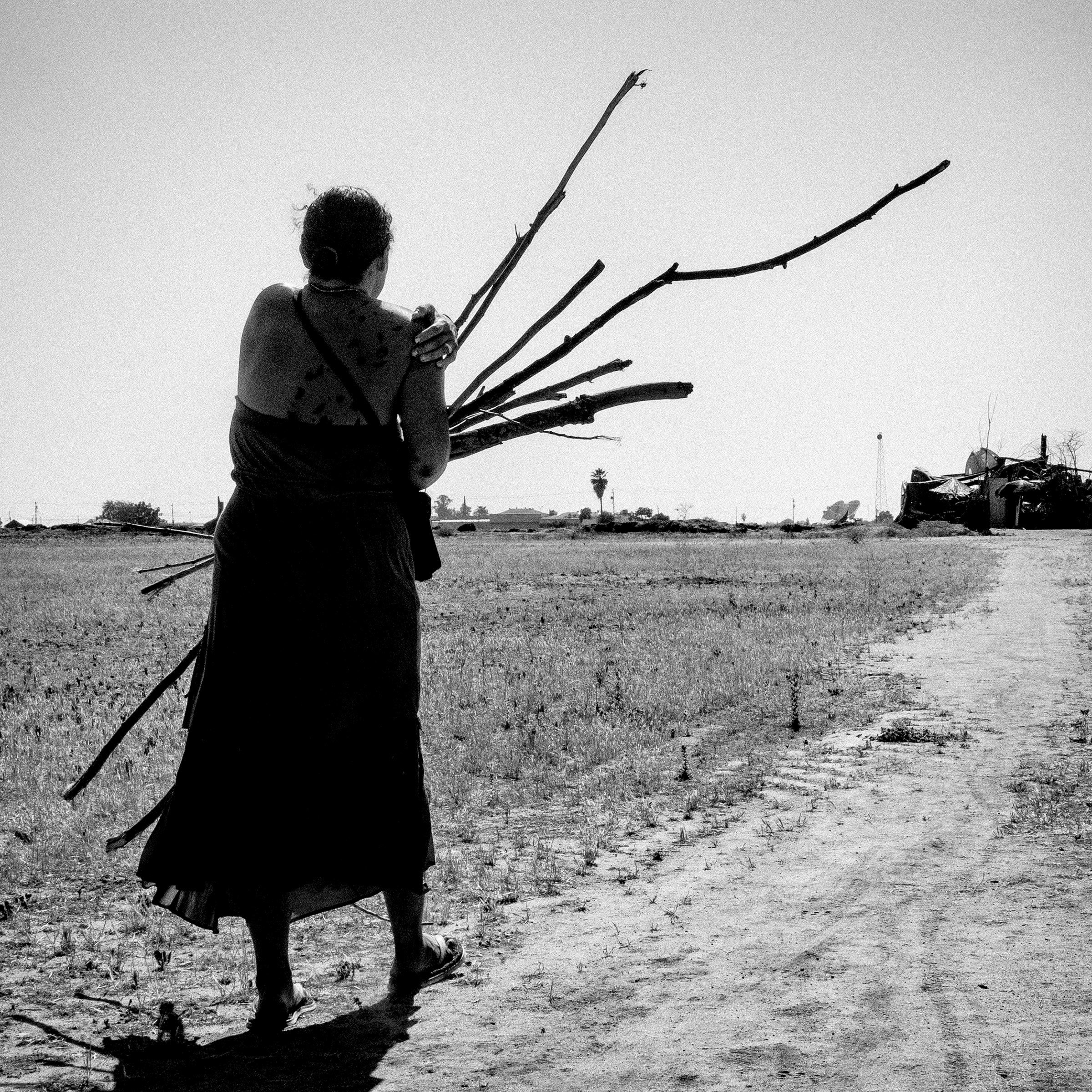 Woman carrying sticks at a homeless camp. Fresno, Calif. 2014.
