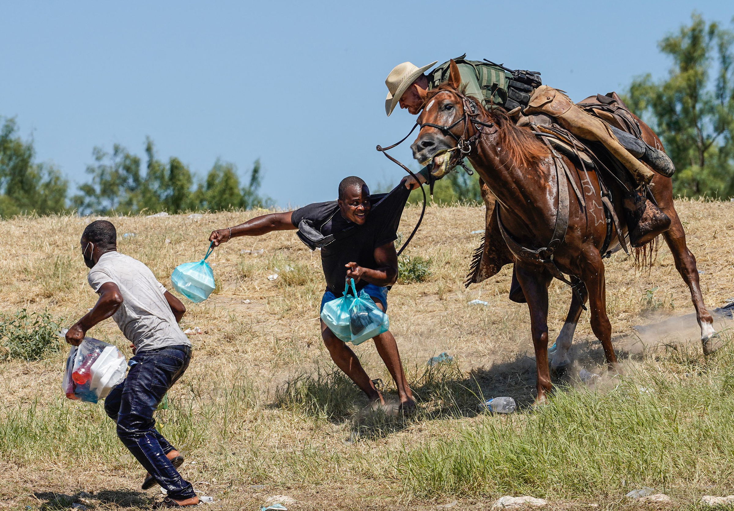 A U.S. Border Patrol agent grabs the shirt of a Haitian man while trying to stop migrants at the U.S.-Mexico border from crossing into Texas, on Sept. 19. Images of mounted agents chasing migrants and brandishing whiplike reins prompted the White House to label the scenes “horrific.” The Department of Homeland Security is investigating.