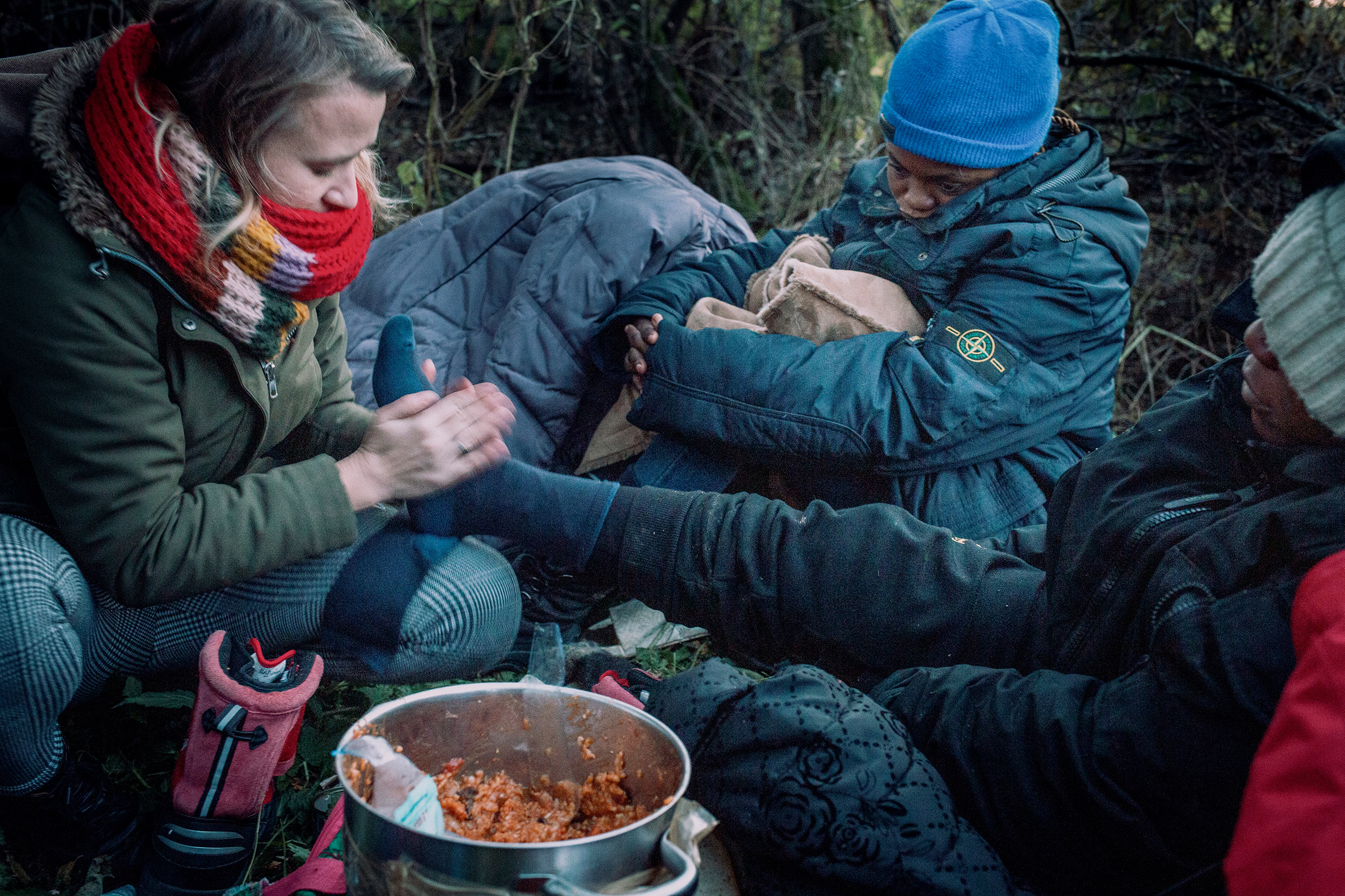 Anna Alboth left, with refugee women from Congo who had been hiding in the forest for 4 days near the Polish-Belarusian border. She is giving food, dry clothes and is warming their feet (Courtesy Thomas Alboth)