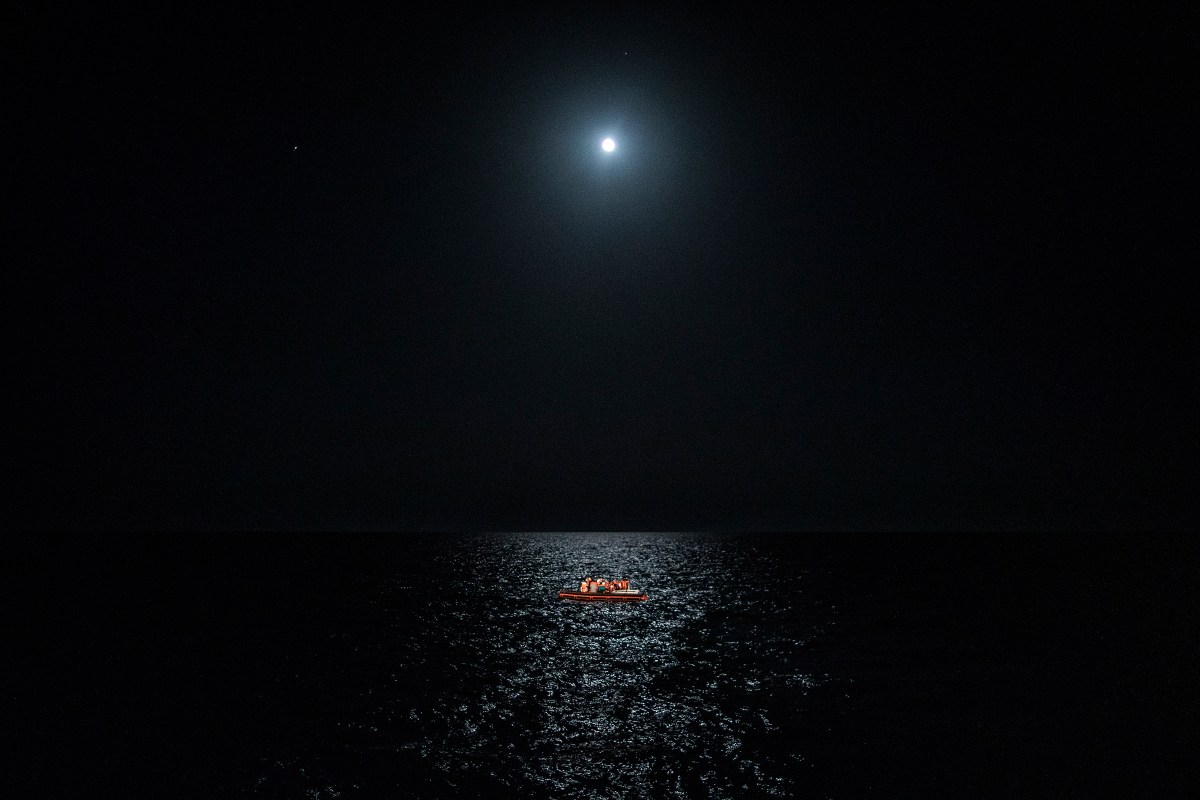 Seventeen people from Tunisia aboard a precarious wooden boat wait for assistance in international waters near the Italian island of Lampedusa on July 25.