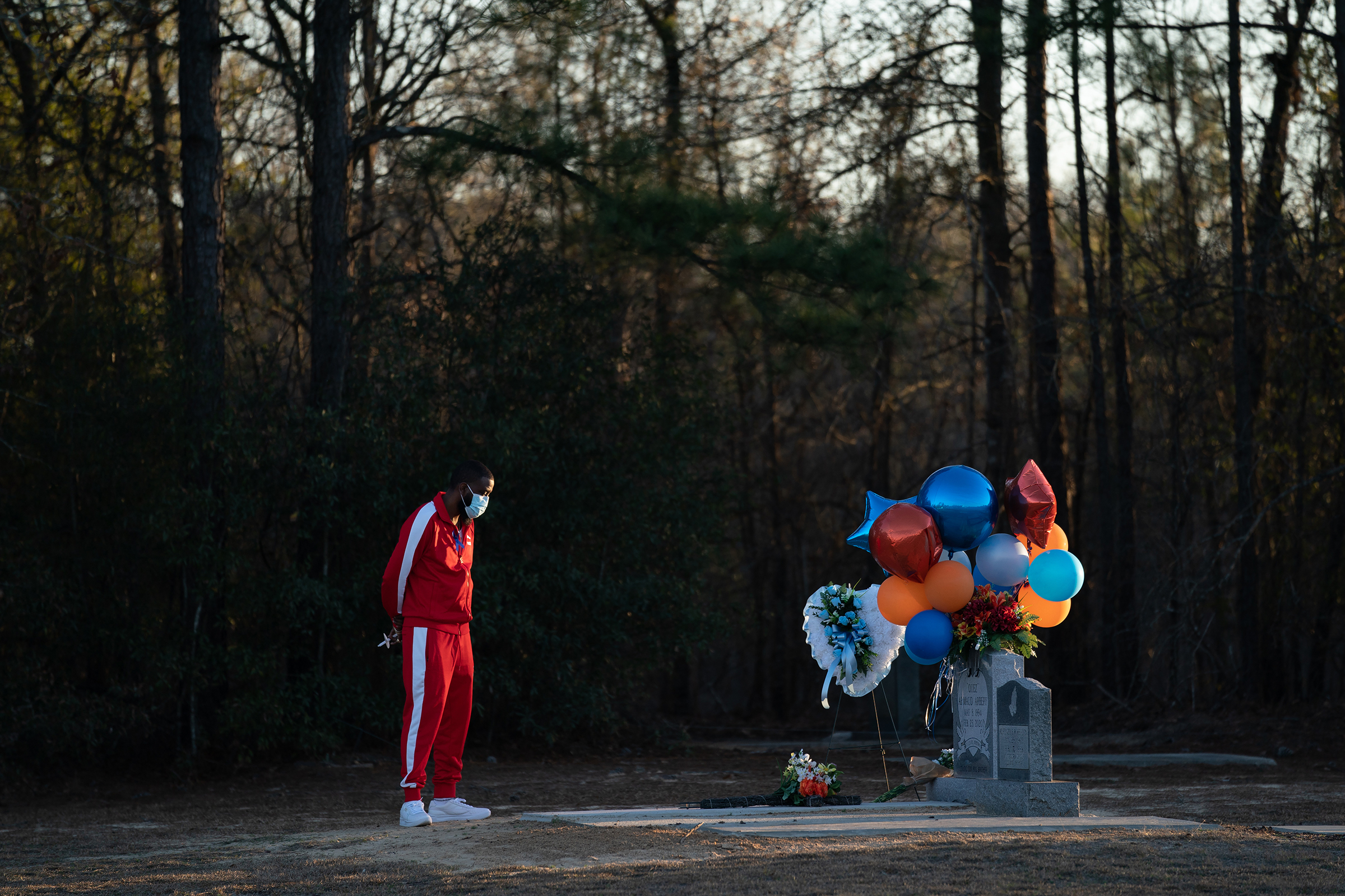 A visitor takes a moment at the gravesite of Ahmaud Arbery in Waynesboro, Ga., on Feb. 23. Arbery, a Black man, was shot and killed while jogging near Brunswick, Ga., a year ago earlier after being chased by white men.