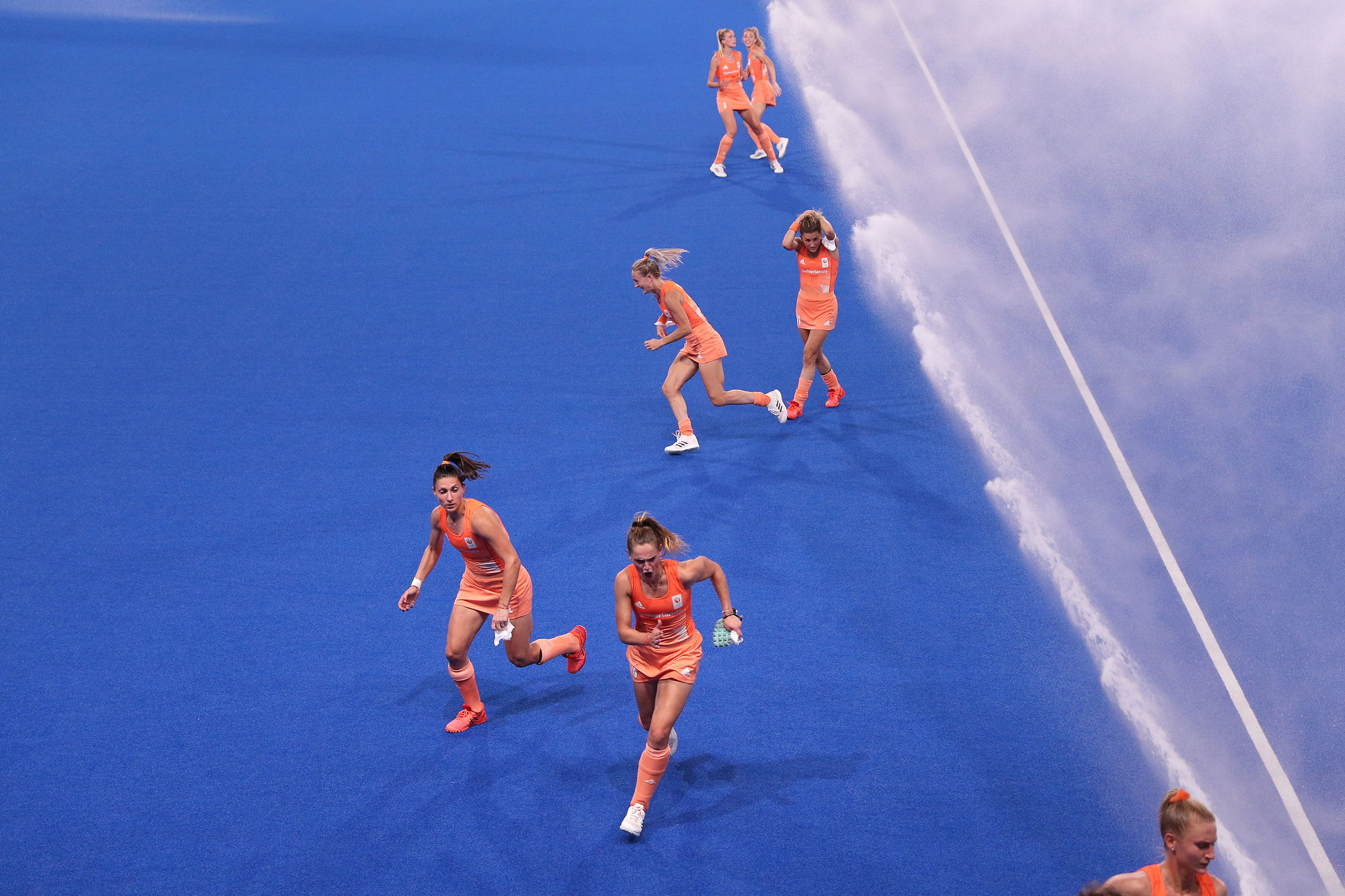 Members of Team Netherlands run from sprinklers ahead of a field hockey match against Germany that determined the Pool A winner at the Tokyo Olympics on July 31. Netherlands won 3-1.