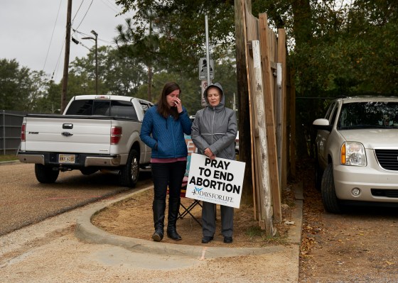 Two people stand outside Jackson Women's Health Center holding pro-life signs