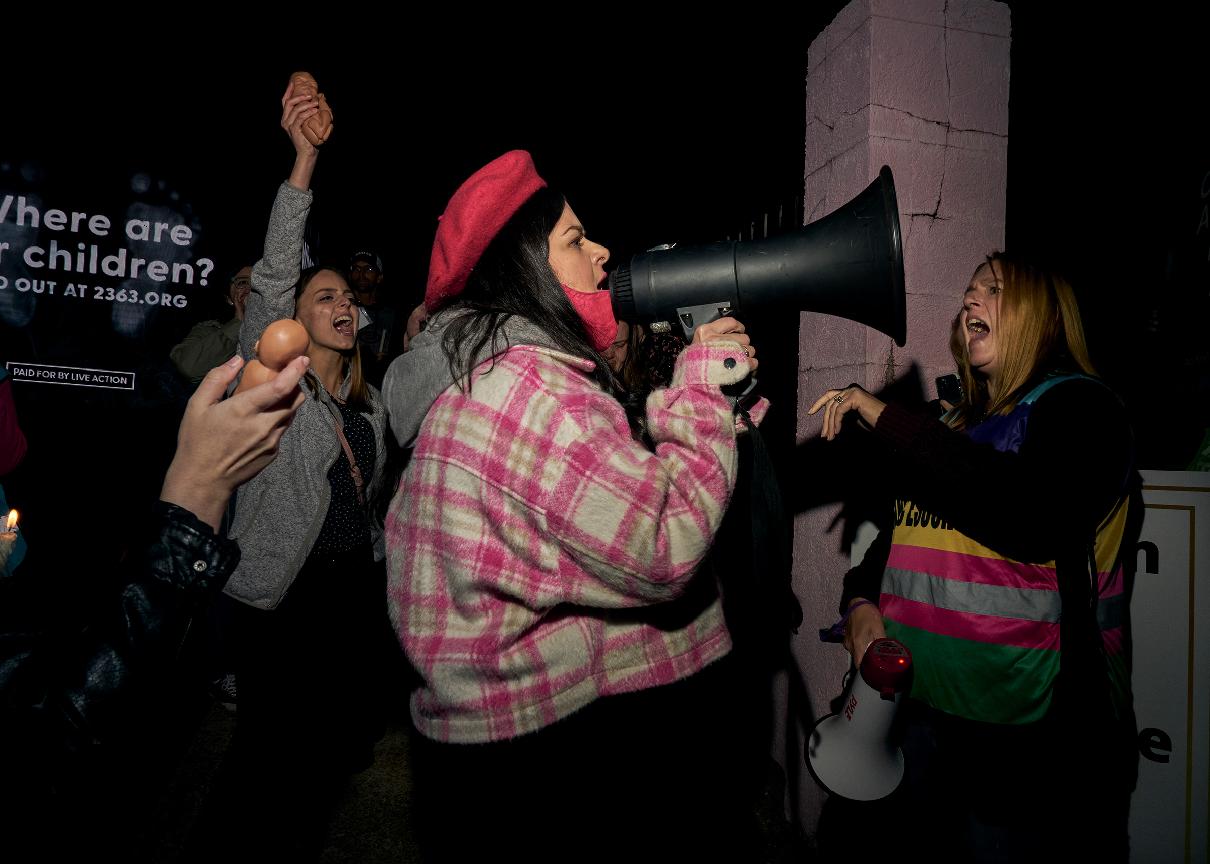 At the Live Action anti-abortion candlelight vigil at Jackson Women's Health Organization on Oct. 29, Kim Gibson (right), clinic escort and co-organizer of the Pink House Defenders, stands in front of the clinic as Terrisa Bukovinac (founder and Executive Director of the Progressive Anti-Abortion Uprising) uses a bullhorn to speak out against abortion (Stacy Kranitz for TIME)
